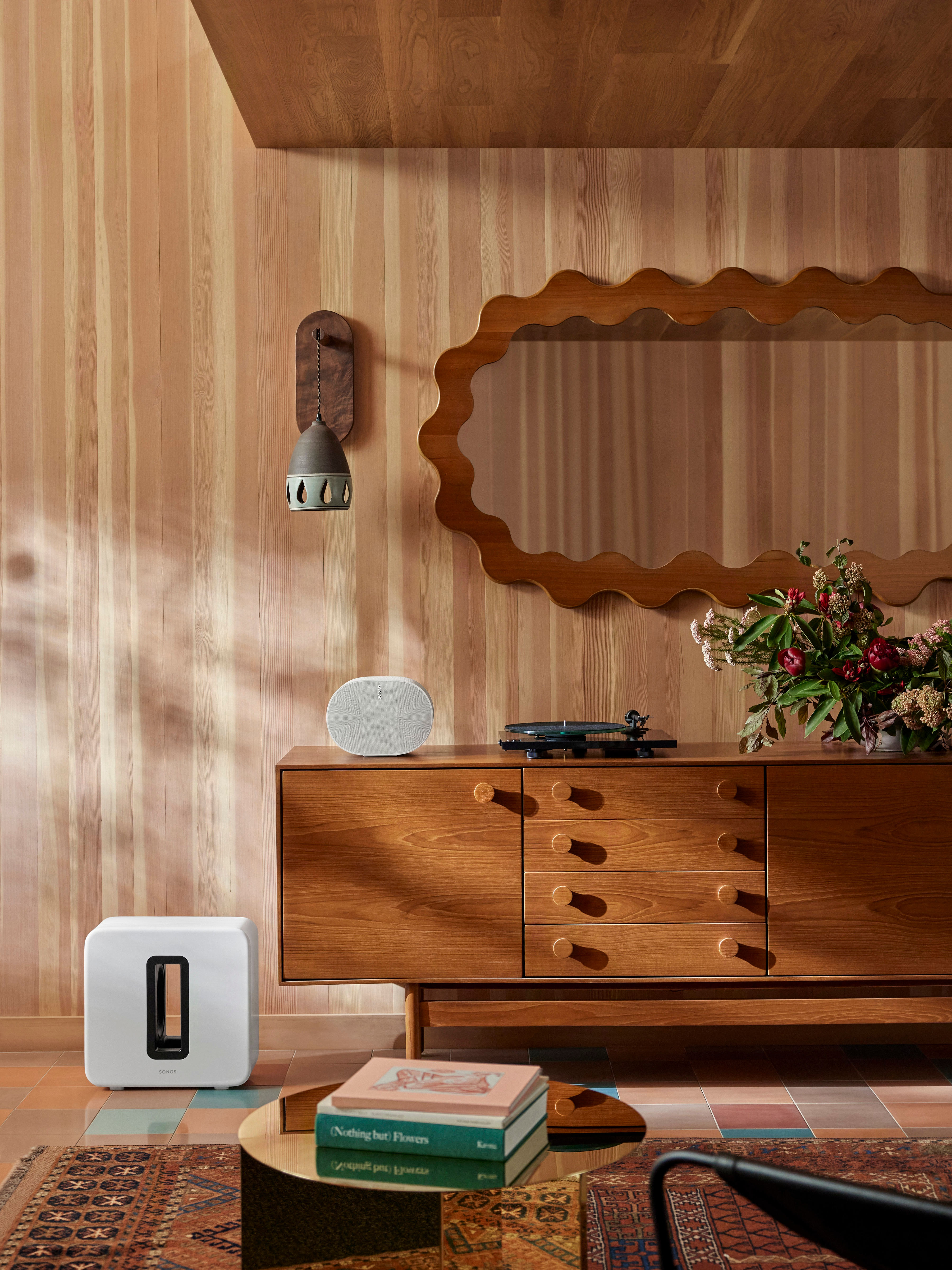 Intérieur élégant avec un caisson de basses blanc, des meubles en bois et un miroir. Platine vinyle sur les meubles.
