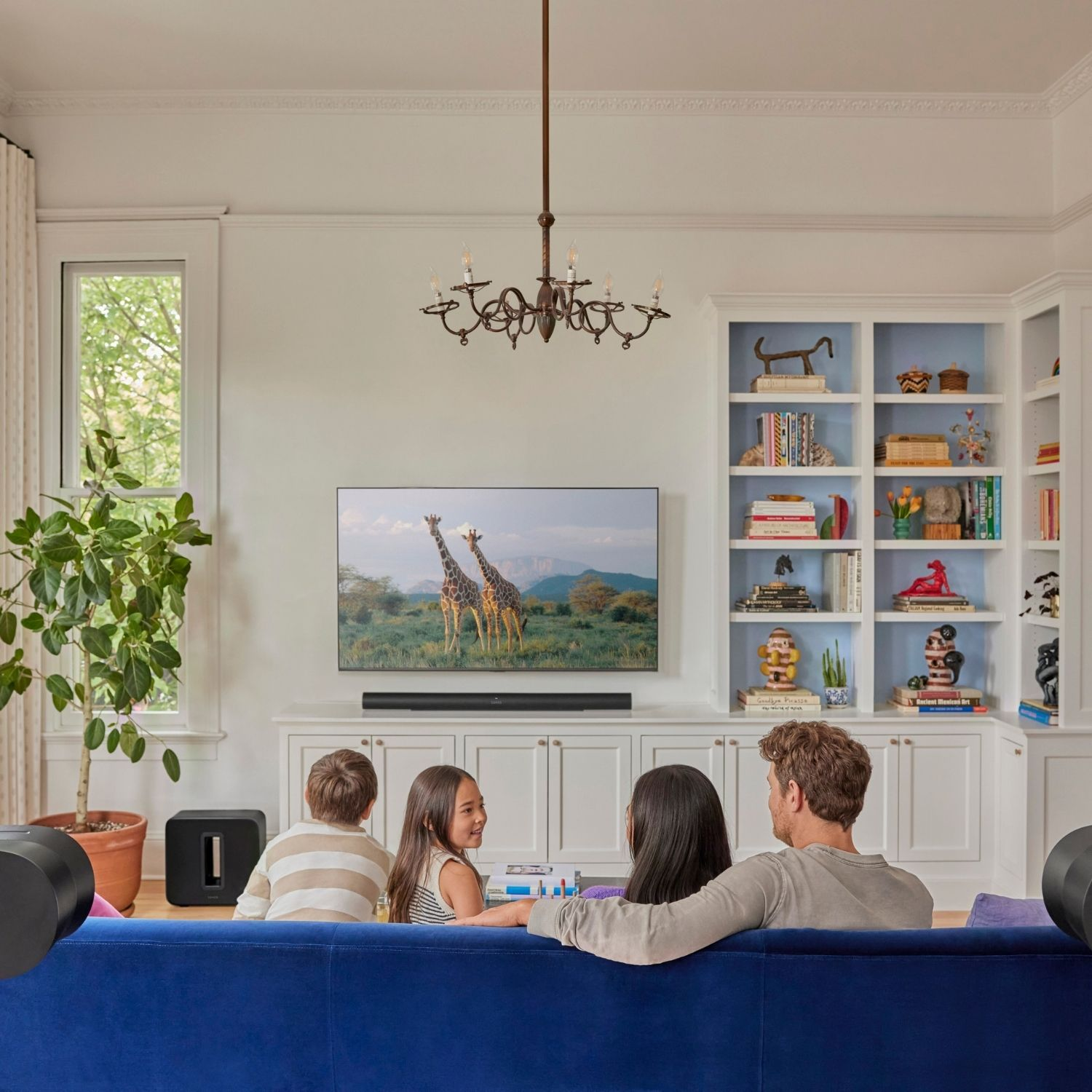 Familia viendo la televisión, un salón con una escena de jirafas en la pantalla.