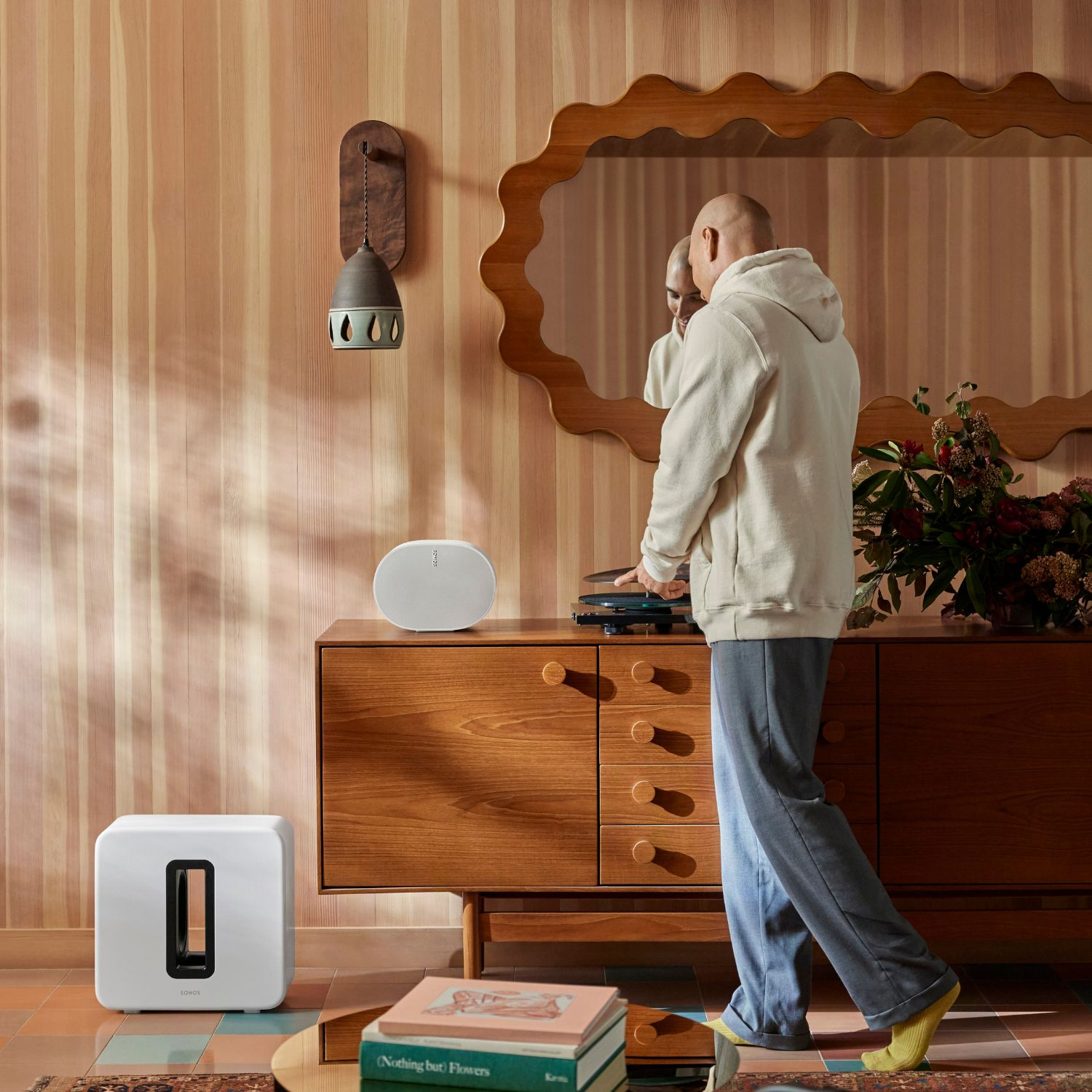 Una persona coloca un disco en un tocadiscos, altavoz blanco y un subwoofer.