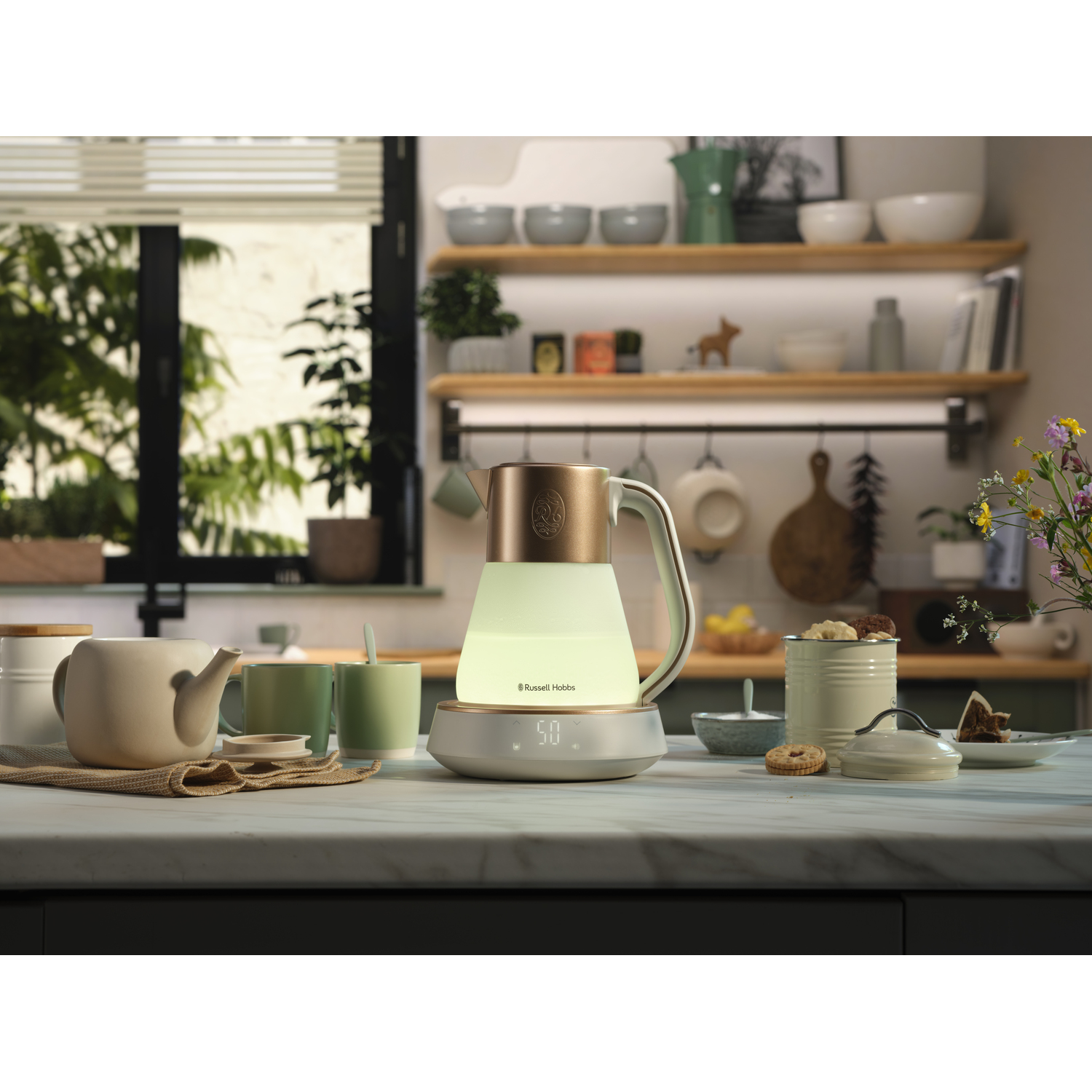 A lit kettle with a gold top and a white base. Other kitchen items are in the background.