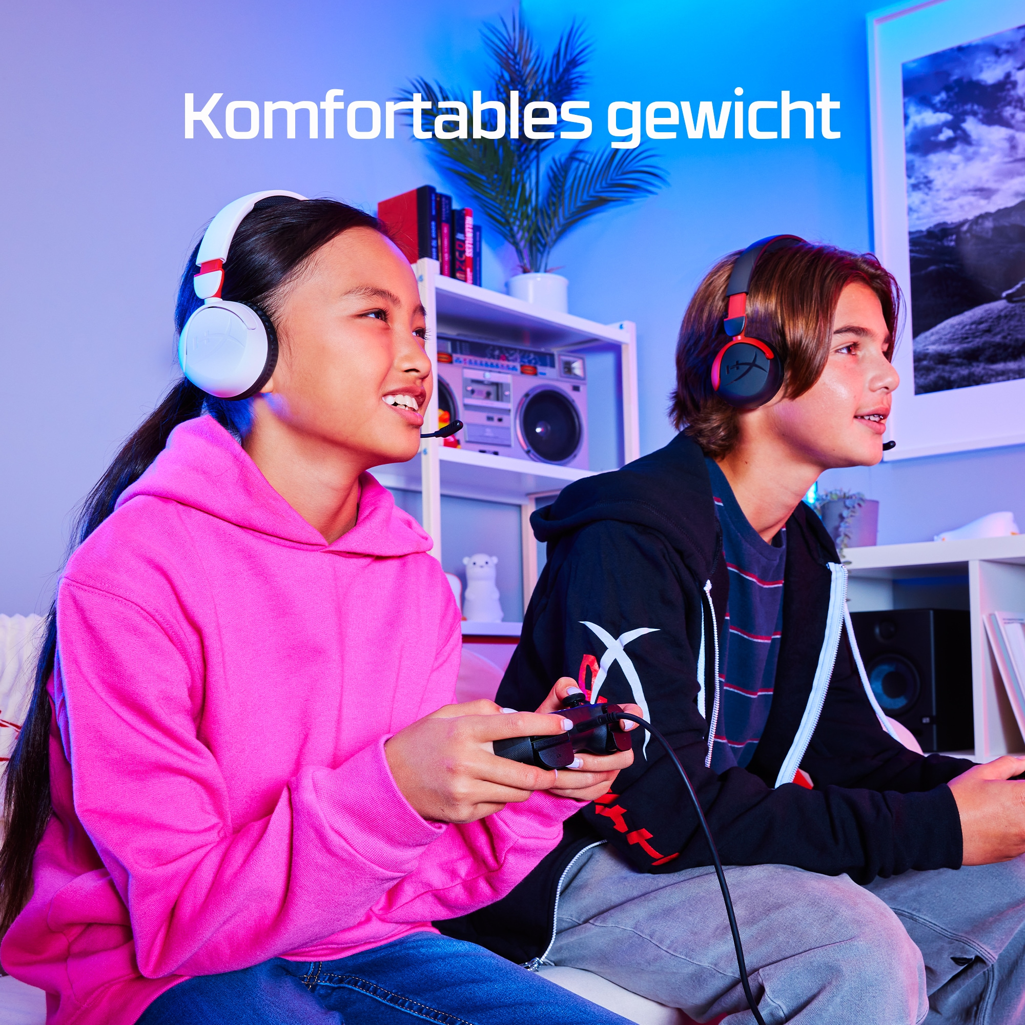 Zwei Teenager tragen Headsets, halten Controller und spielen Videospiele. Pinke und schwarze Hoodies.