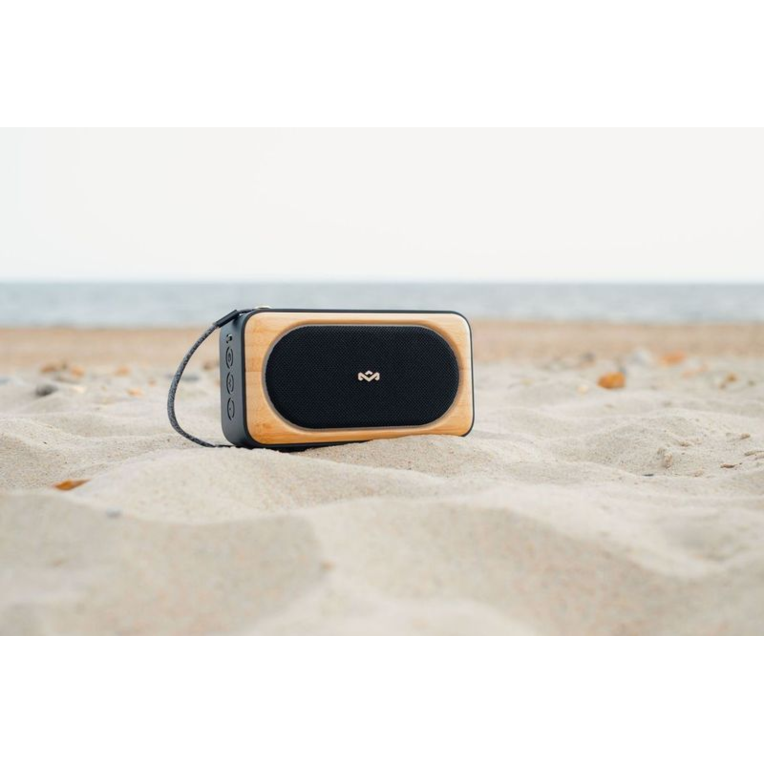 A wooden speaker on sand at the beach.