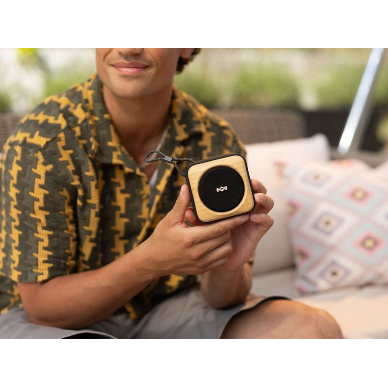A man holding a small, square wooden speaker.
