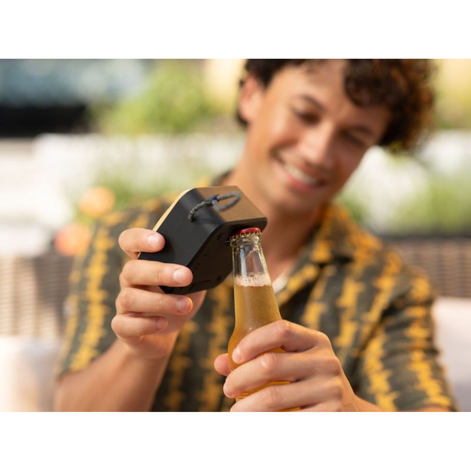 Man opening a beer bottle with a black bottle opener.