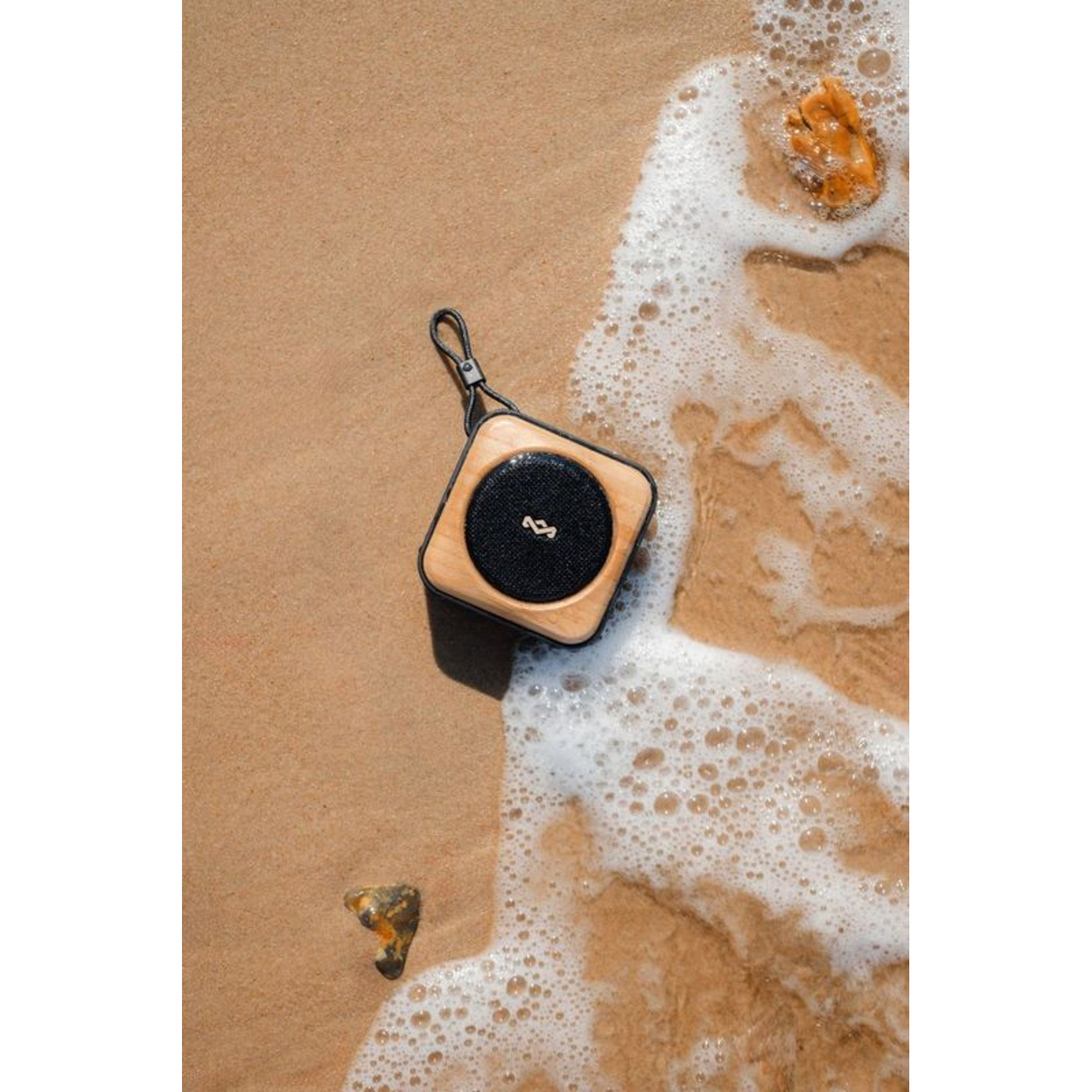 Portable speaker on the beach, sand, water.