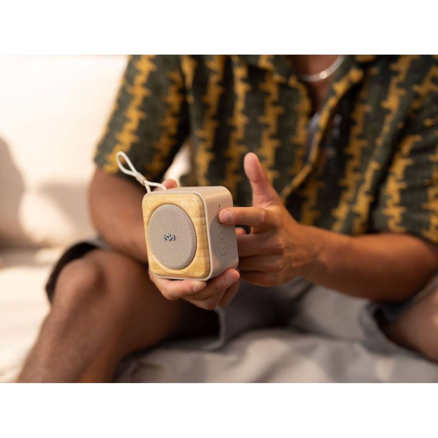 Persoon die een kleine, licht houten en grijze speaker vasthoudt.