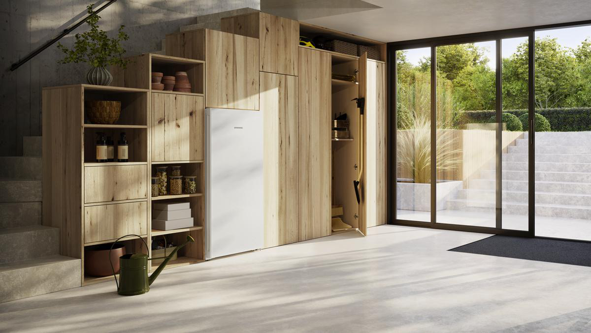 Ein modernes Interieur. Holzaufbewahrung, ein weißer Kühlschrank und eine Treppe führen hinunter.