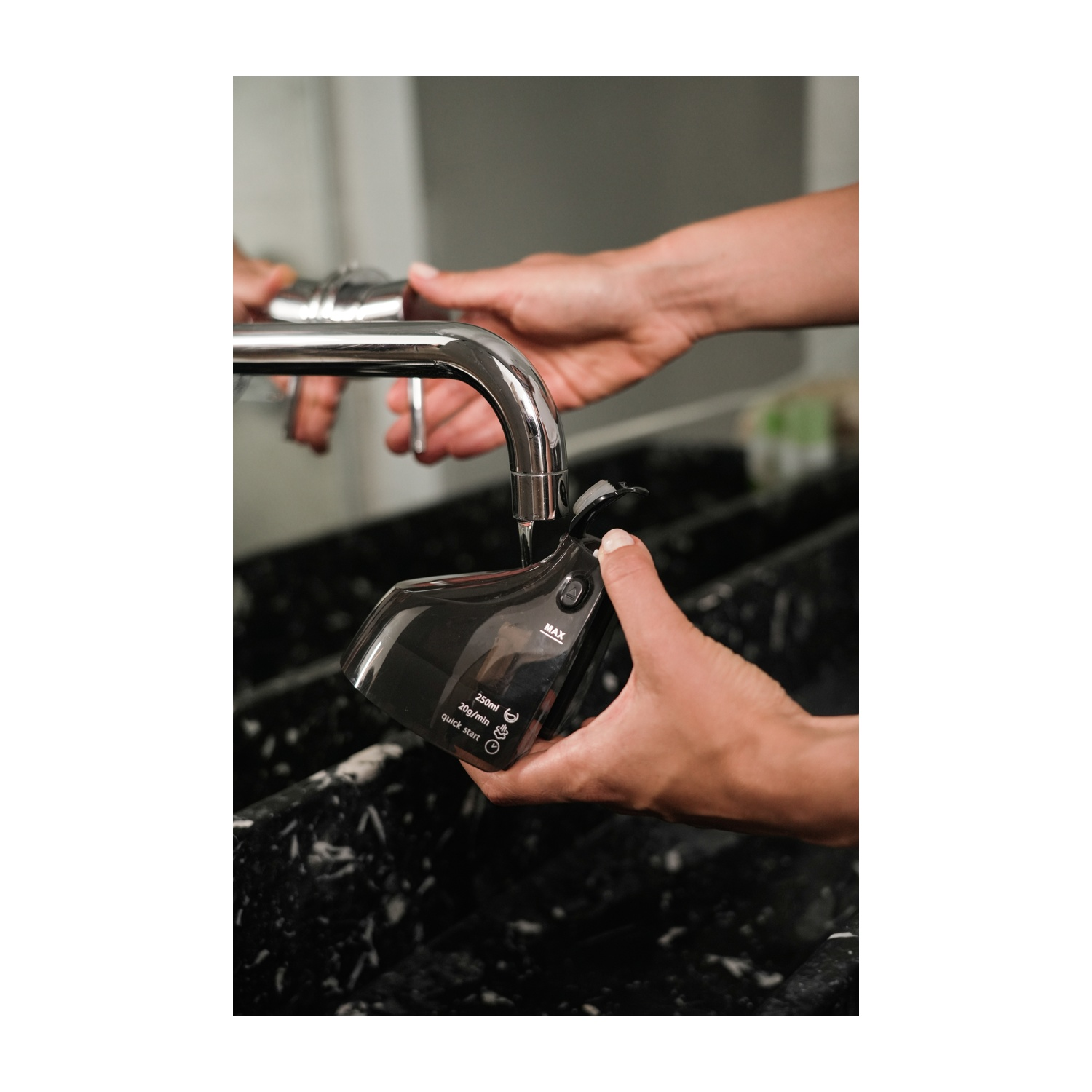 Mani che riempiono un contenitore nero con acqua sotto un rubinetto. Il contenitore ha impostazioni.