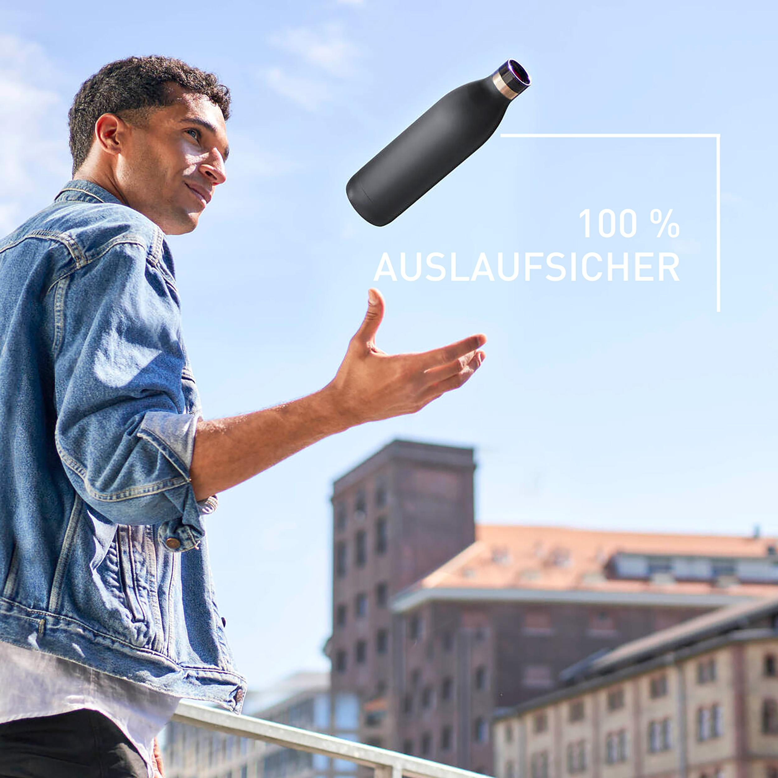Ein Mann wirft eine schwarze Flasche in die Luft, mit Stadt im Hintergrund.