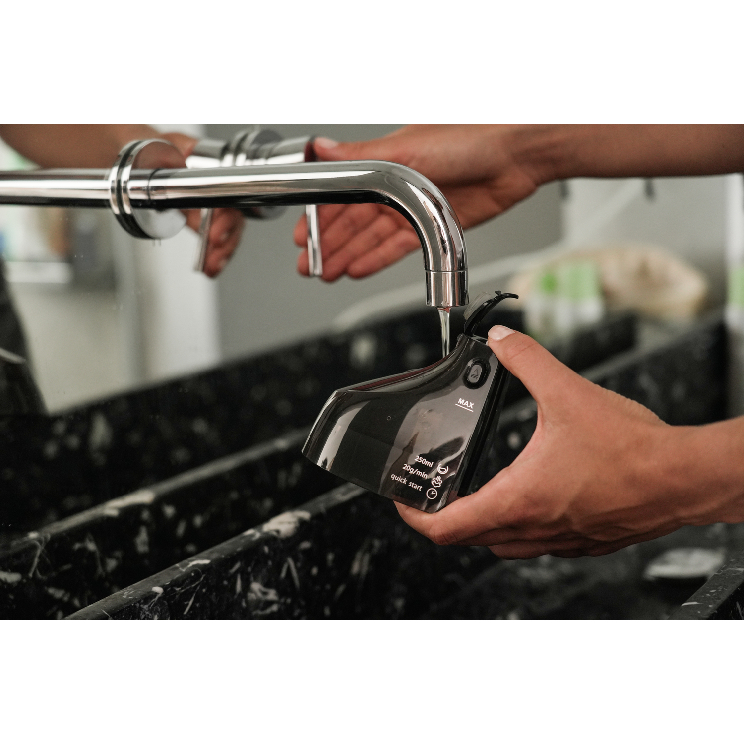 Een persoon gebruikt een waterdispenser om een zwart apparaat met water te vullen.