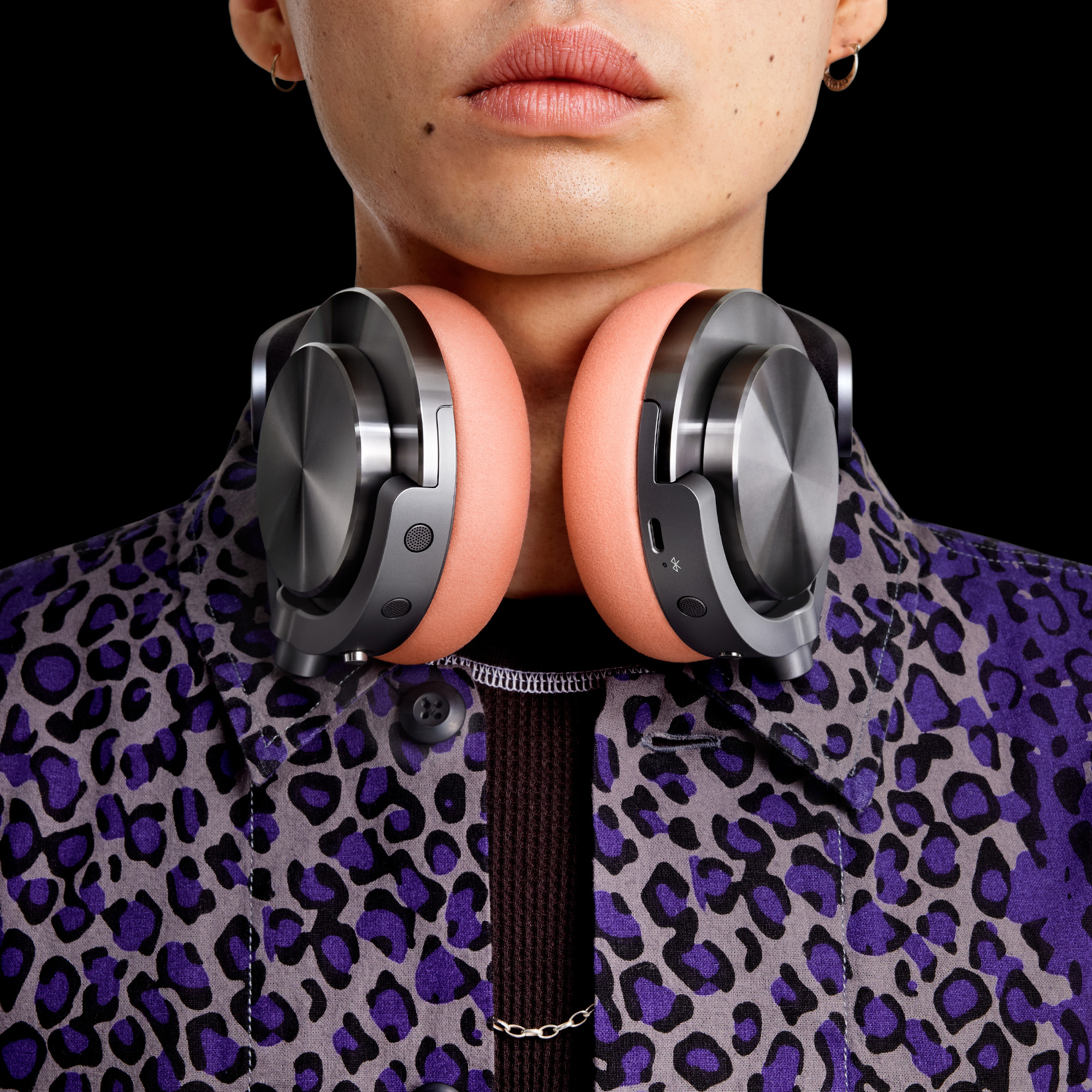 Osoba w słuchawkach, w kurtce i na czarnym tle.