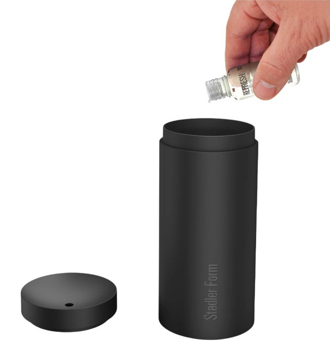 Ręka wlewa płyn z butelki do czarnego cylindrycznego pojemnika. Pokrywa po lewej stronie.