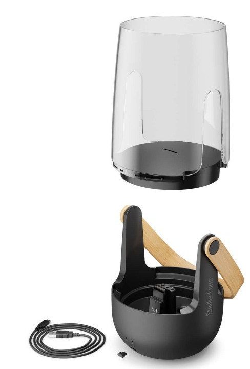 Dwie części urządzenia, górna jest przezroczysta, cylindryczna, a dolna czarna i ma drewniane uchwyty.