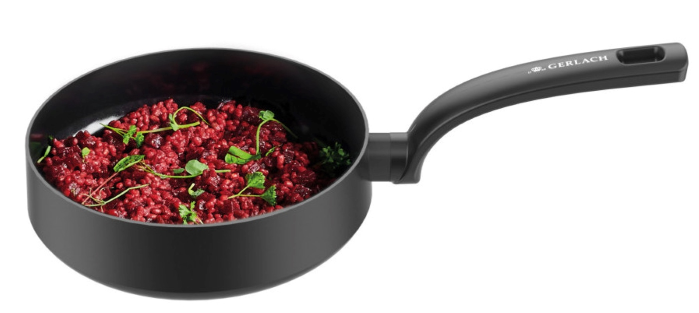 Czarna patelnia wypełniona czerwonym jedzeniem i udekorowana zielonymi ziołami.