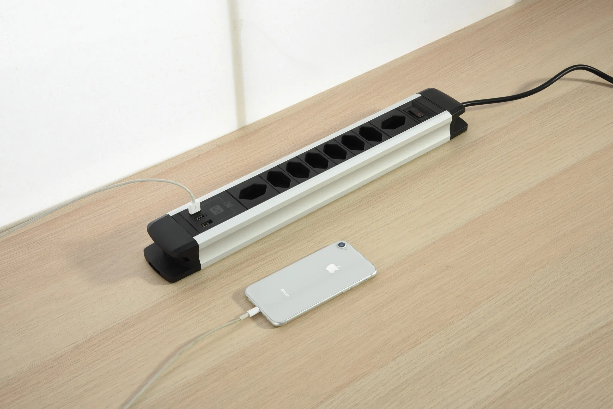 Steckdosenleiste mit Steckdosen, USB-Anschlüssen und Telefonladung. Auf Holz.