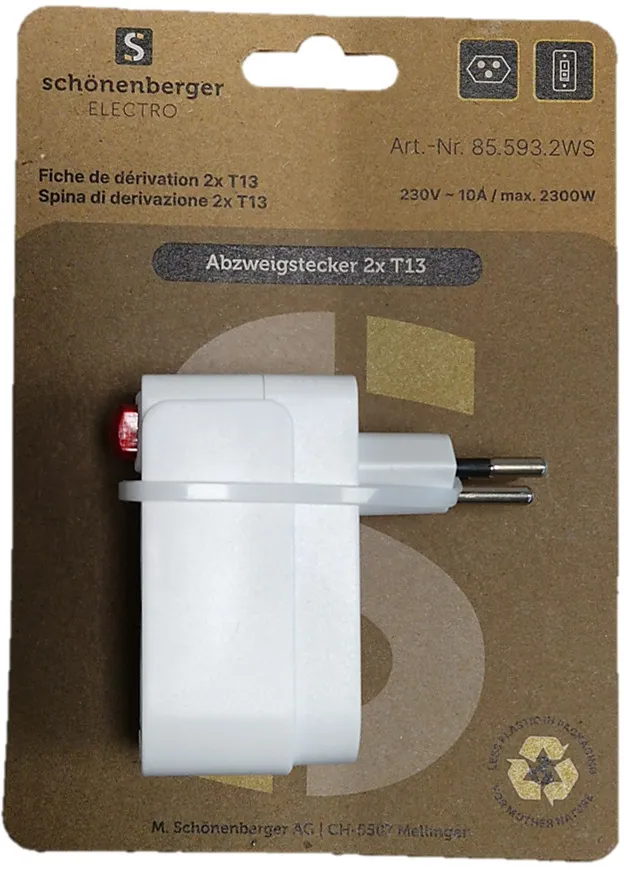Ein weißer Adapter mit zwei Stiften und einem roten Knopf auf einer braunen Pappverpackung.