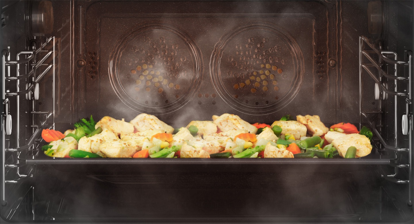 Poulet et légumes cuisant à la vapeur dans un four.