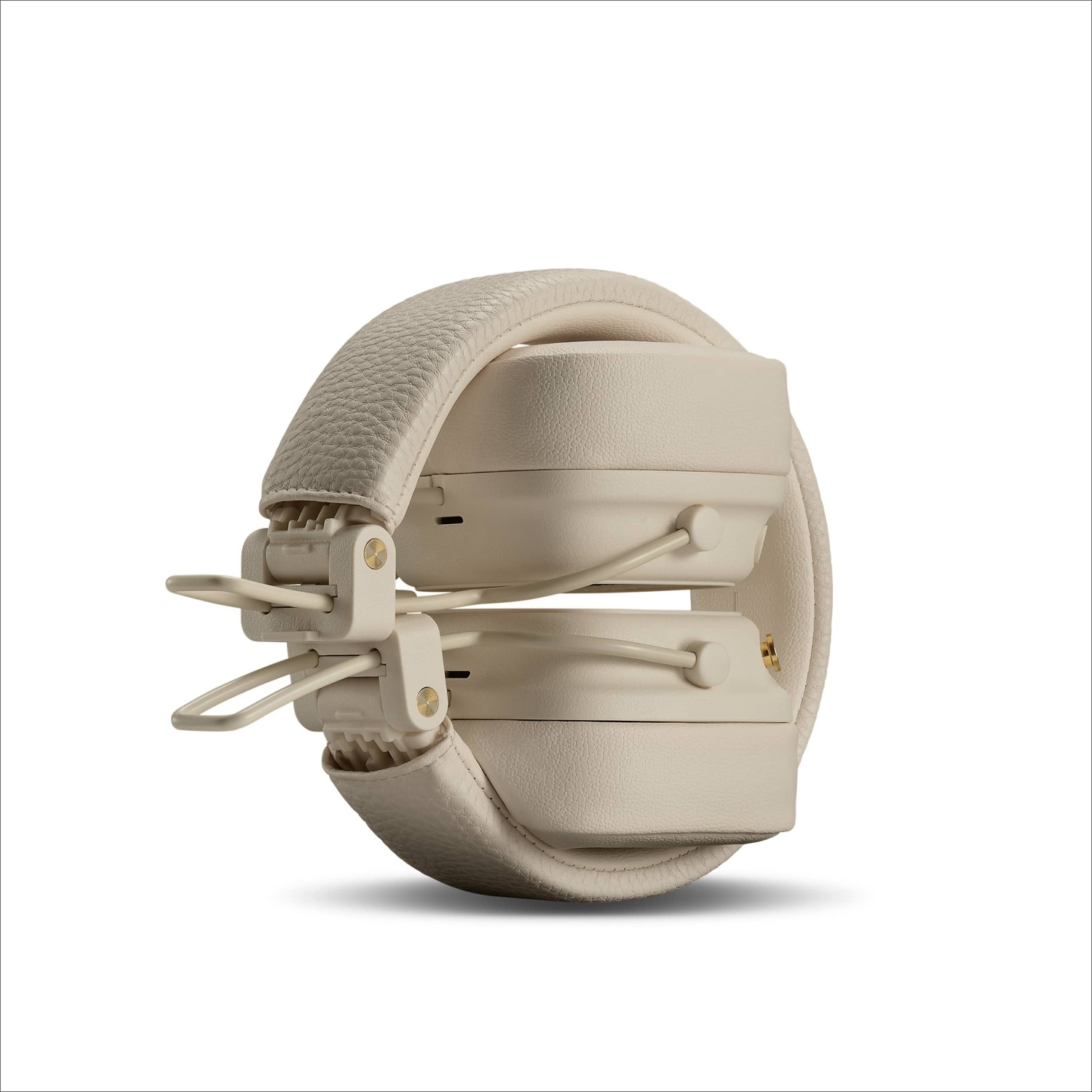 Folded cream-colored Marshall headphones, white background, side view.