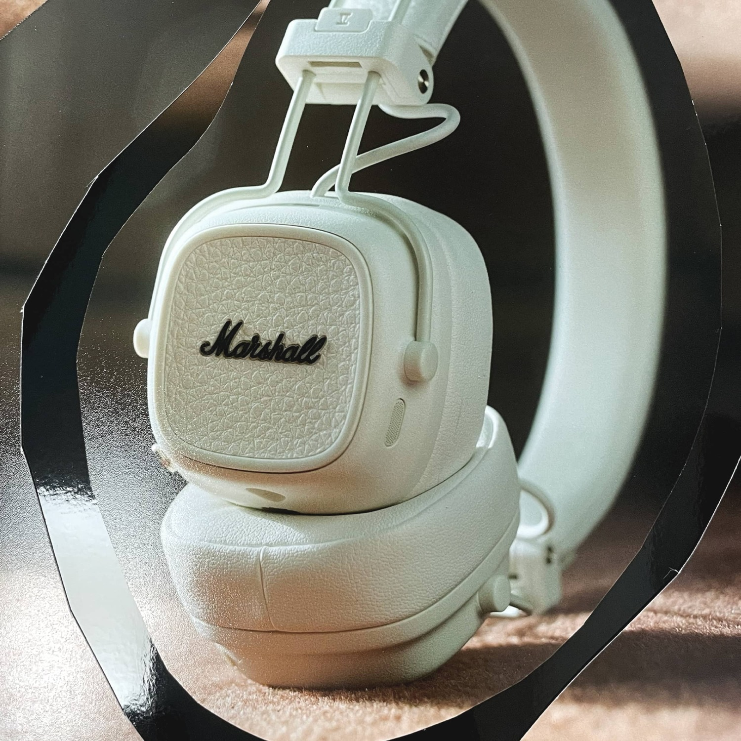 White Marshall headphones on a brown surface, with black frame accents.