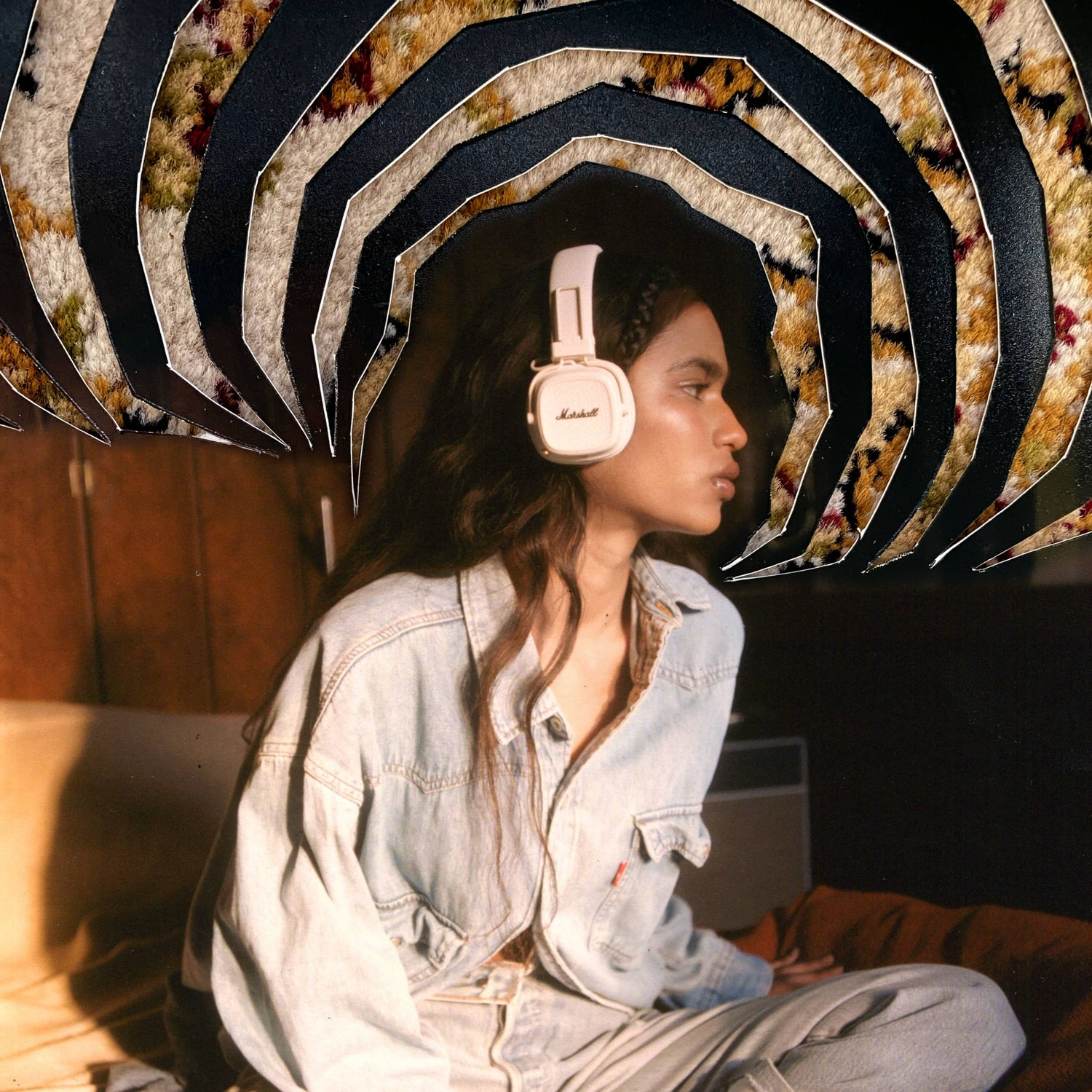 A woman wearing headphones sits with a denim jacket, under a carpet-like design above.