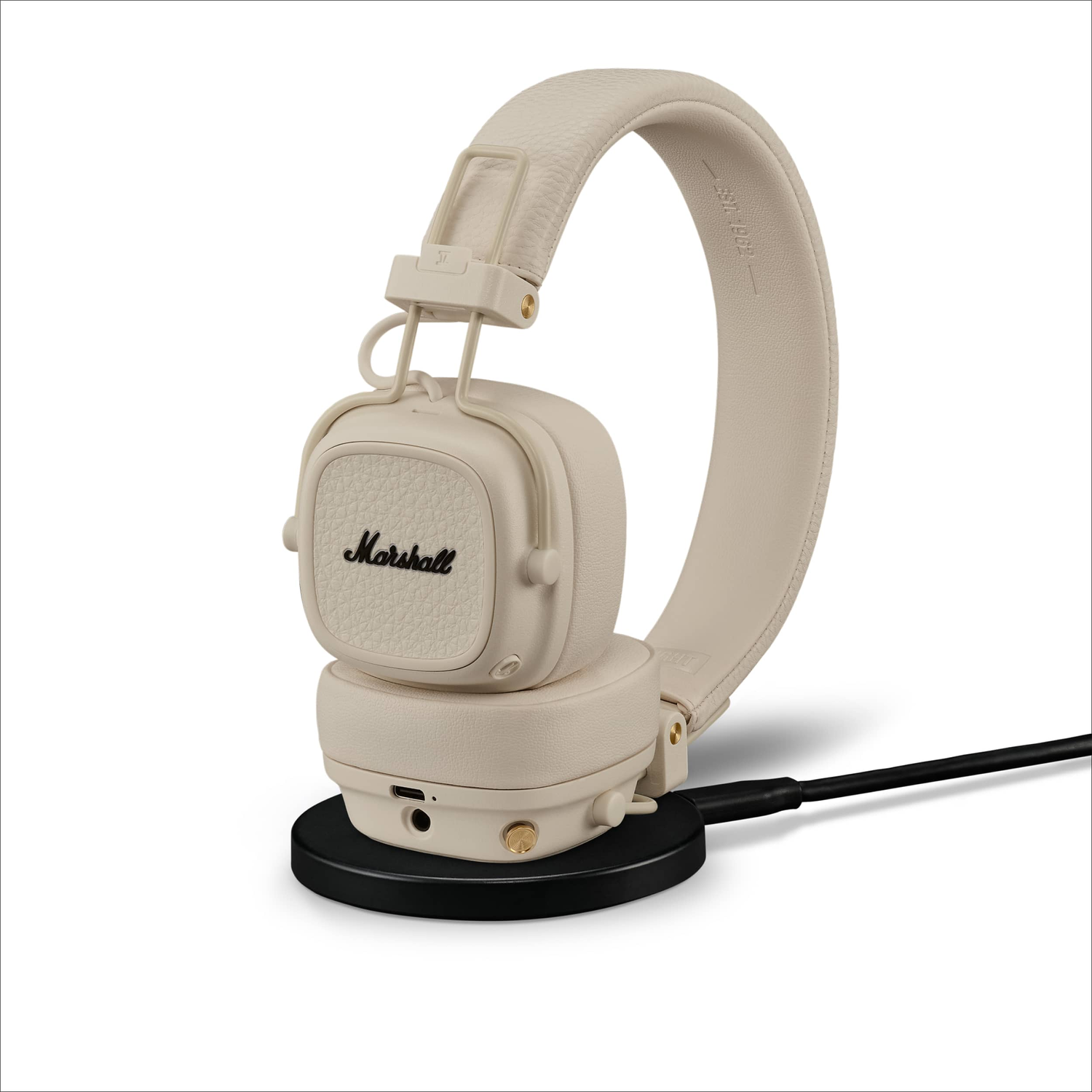 Beige Marshall headphones on a black charging base.
