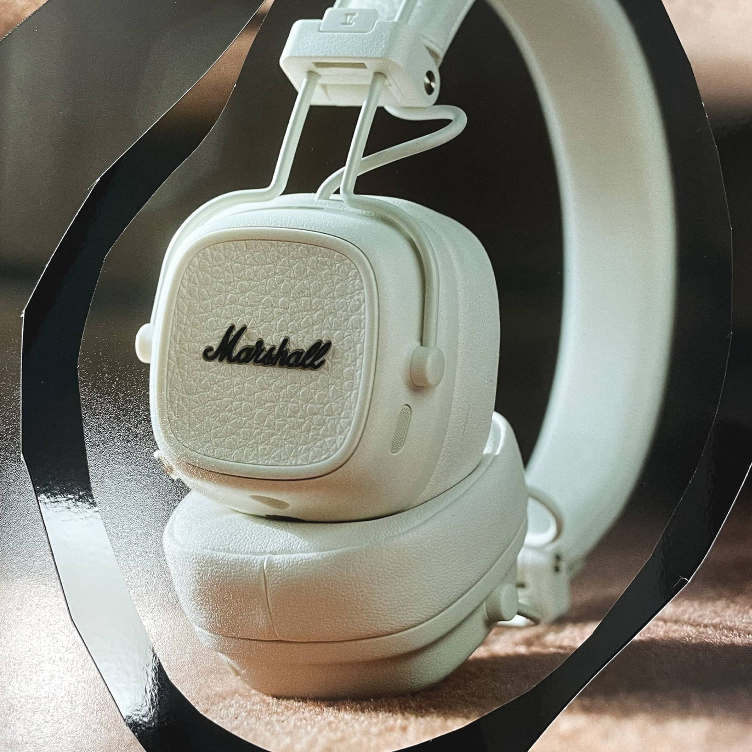 White Marshall headphones, close up. The brand name is visible on the ear cup.