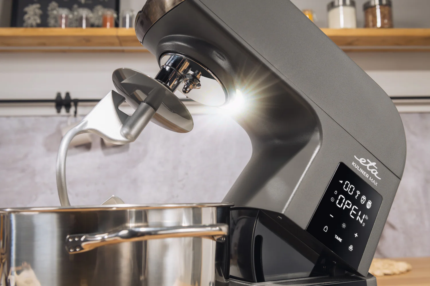 Szürke konyhai mixer közeli képe, tartozékokkal, erős fénnyel megvilágítva.