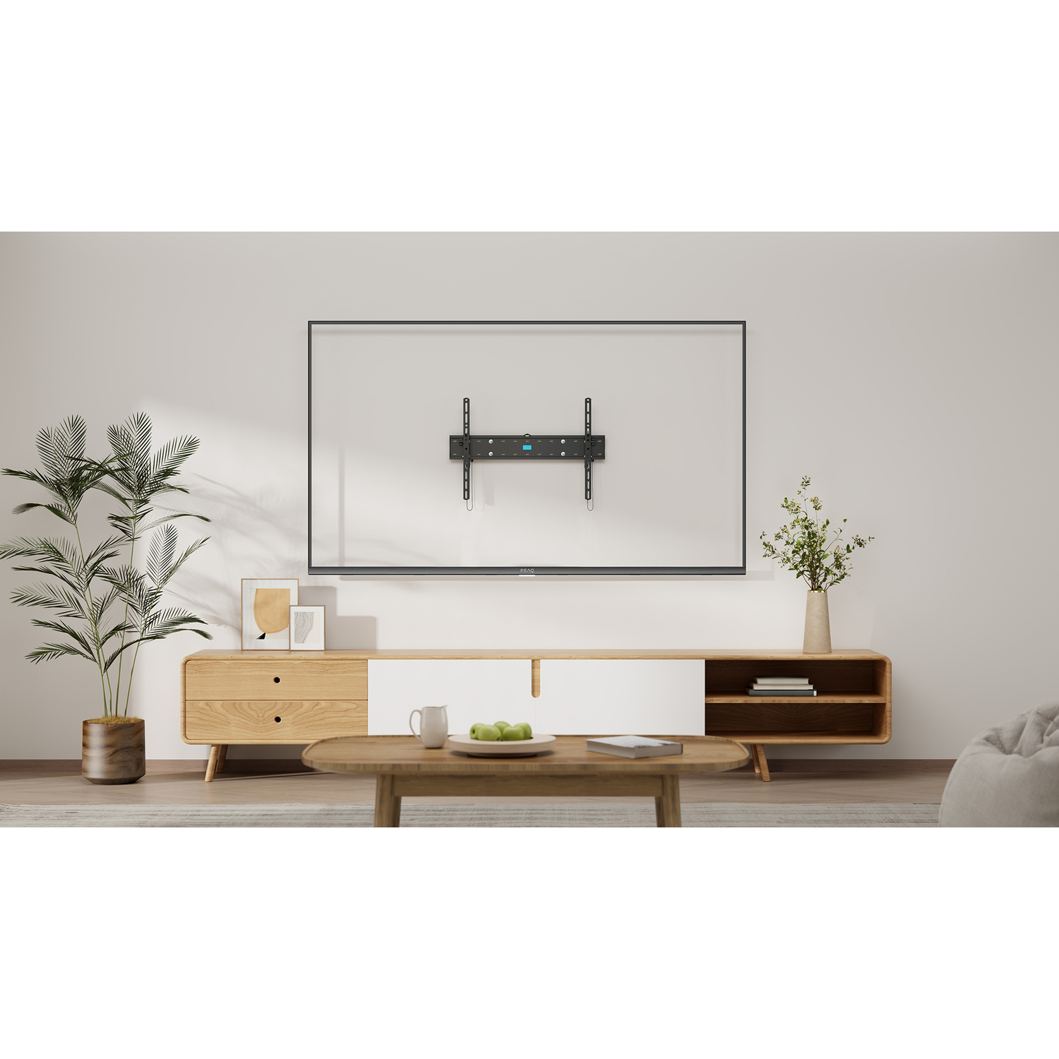 Une télévision murale. Un meuble en bois se trouve en dessous, avec une plante et des fleurs de chaque côté de la télévision.