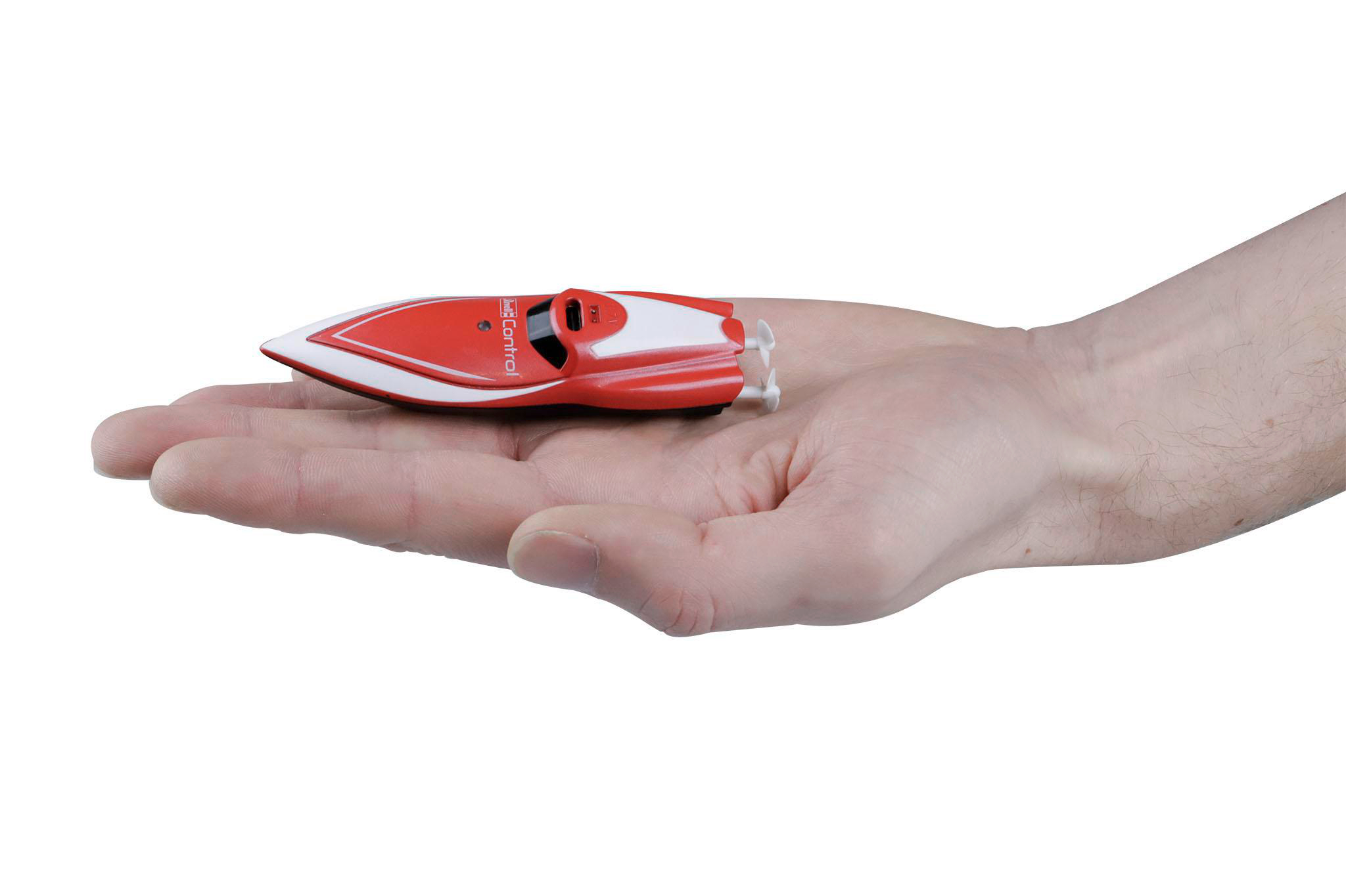 Ein kleines, rot-weißes Spielzeugboot wird in einer Hand gehalten. Das Boot wird vor weißem Hintergrund gehalten.