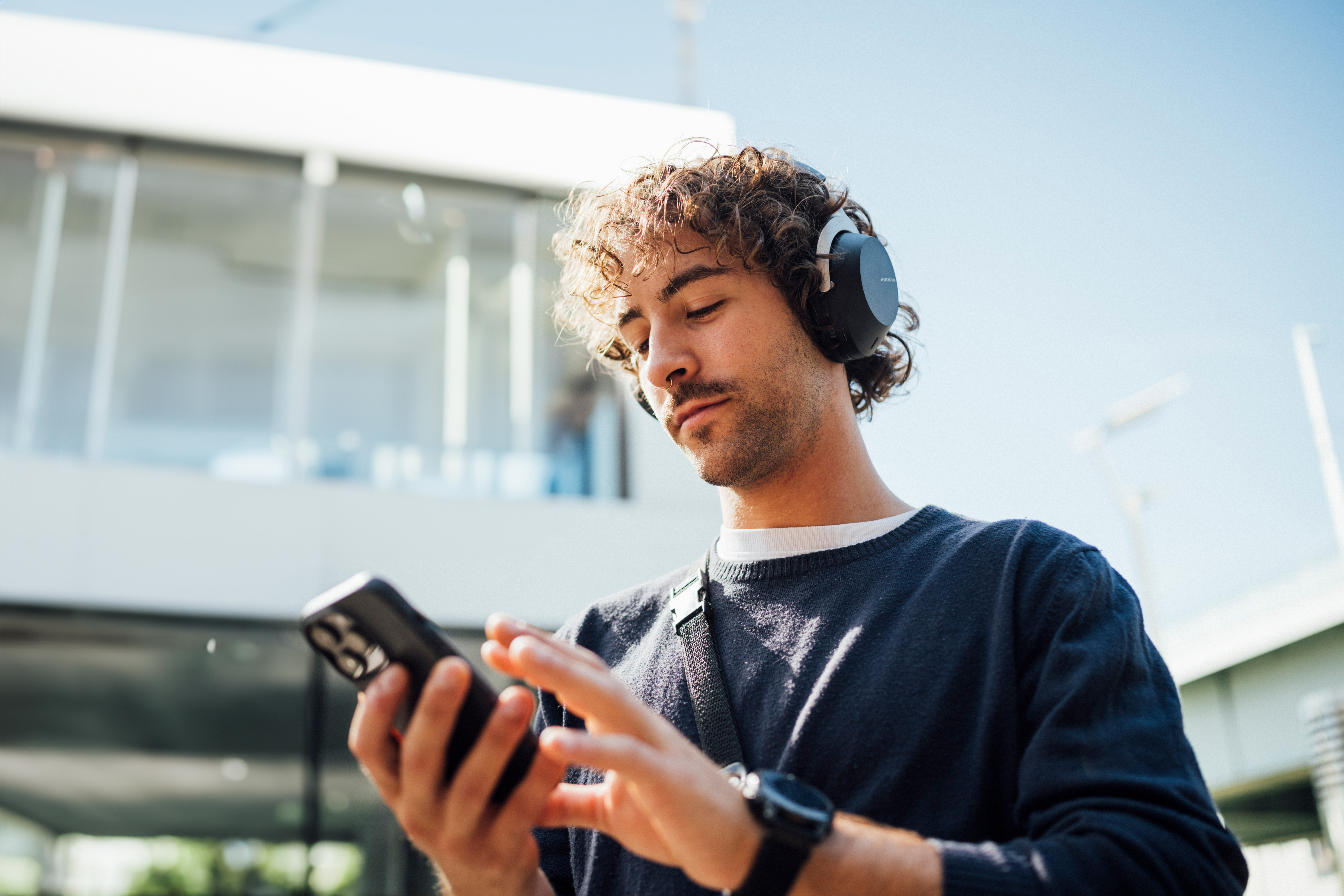 Uomo che usa un telefono all'aperto, con le cuffie.
