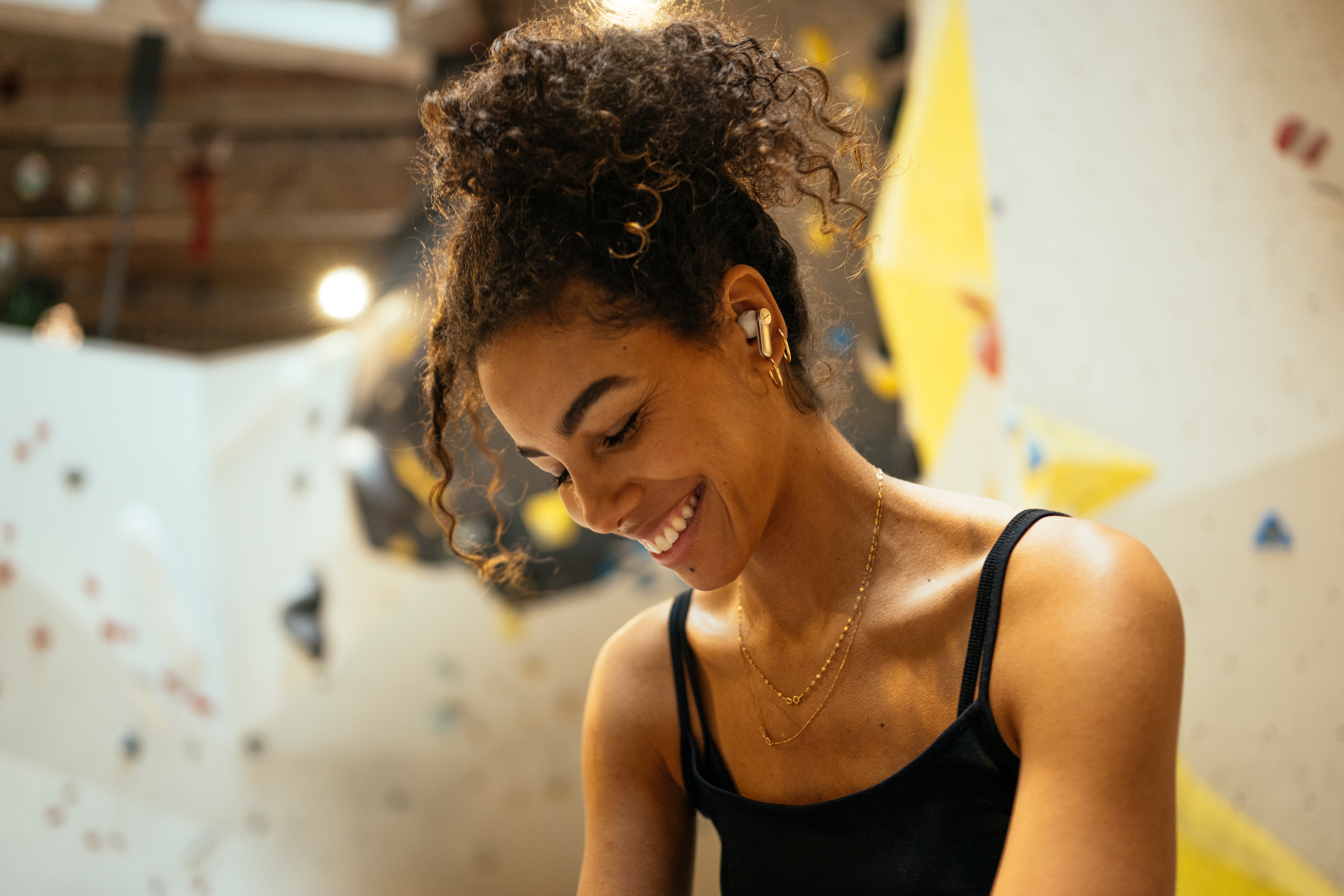 Donna sorridente con auricolari wireless in una palestra di arrampicata.