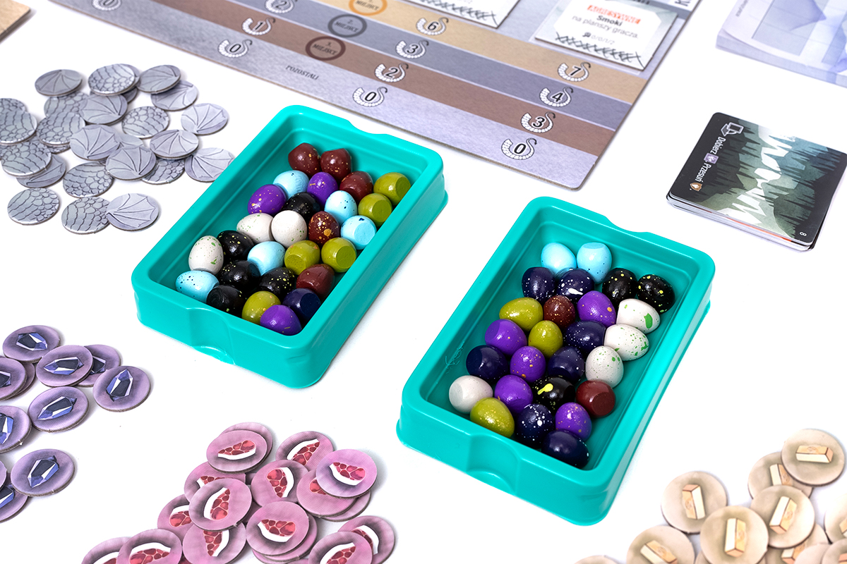 Elementy gry planszowej, w tym kolorowe pionki i plansza do gry.