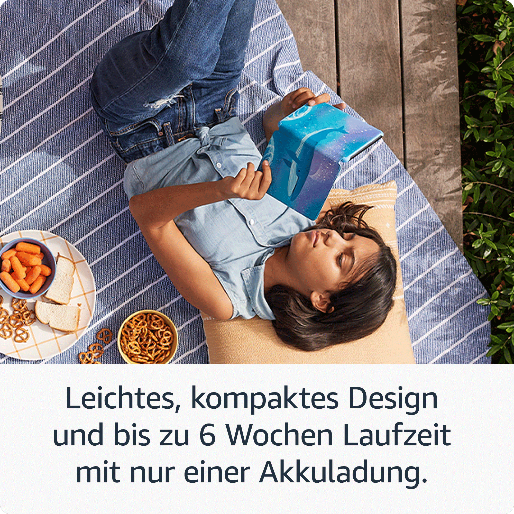 Ein Mädchen liegt auf einer Picknickdecke und liest auf einem blauen Tablet.