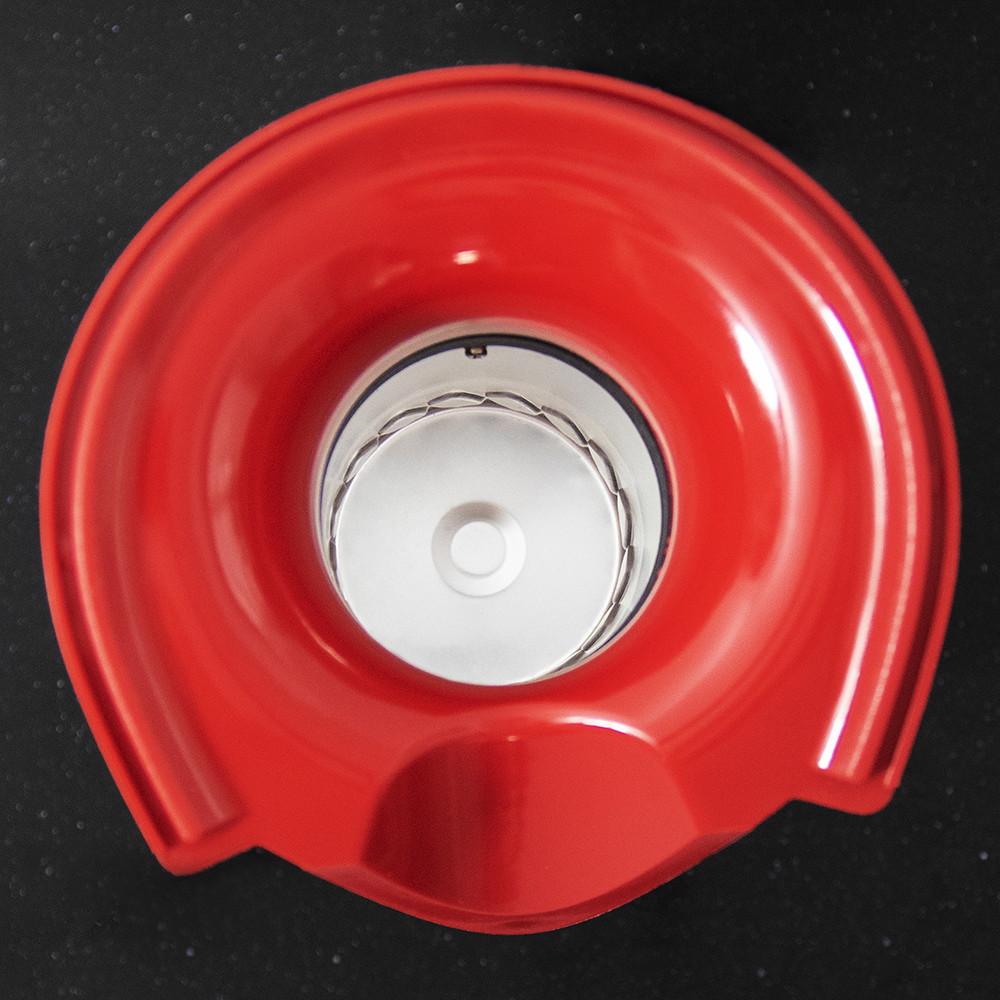 Una tapa roja de un dispositivo sobre un fondo negro.