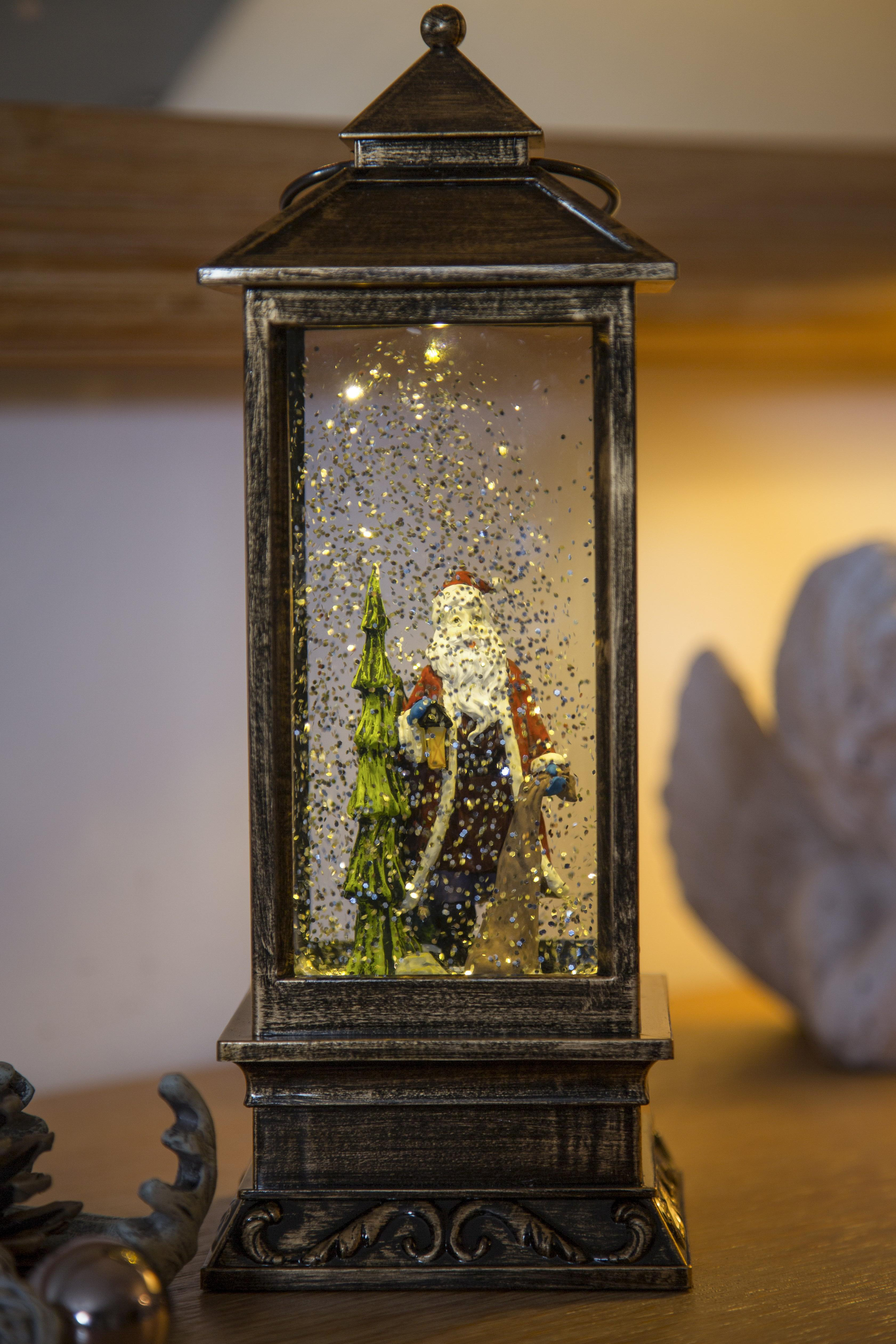 Eine weihnachtliche Schneekugel-Laterne mit Weihnachtsmann und Weihnachtsbaum, gefüllt mit Glitzer.