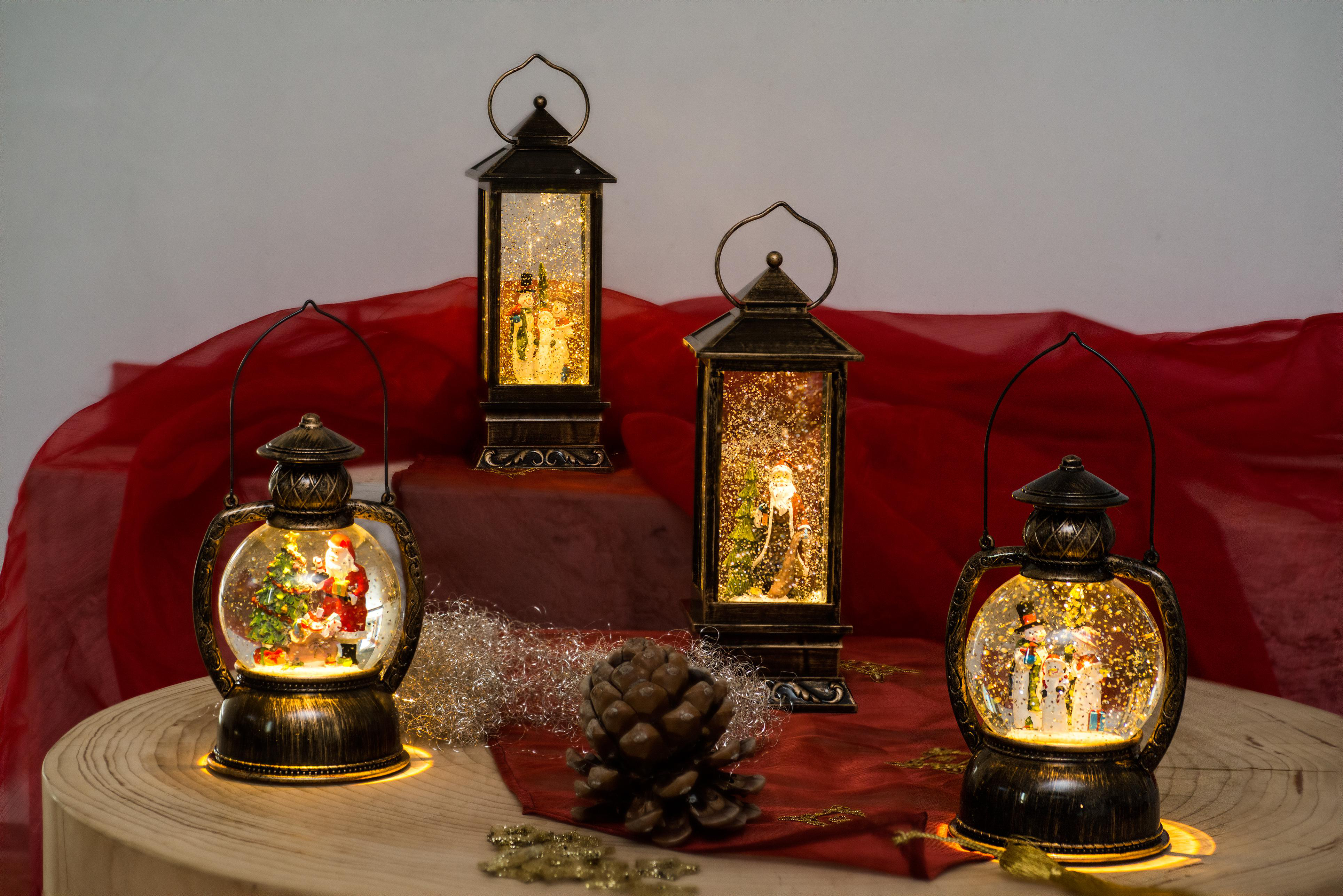 Drei Weihnachtsschneekugeln mit Lichtern im Inneren. Eine mit dem Weihnachtsmann, die anderen mit Figuren.