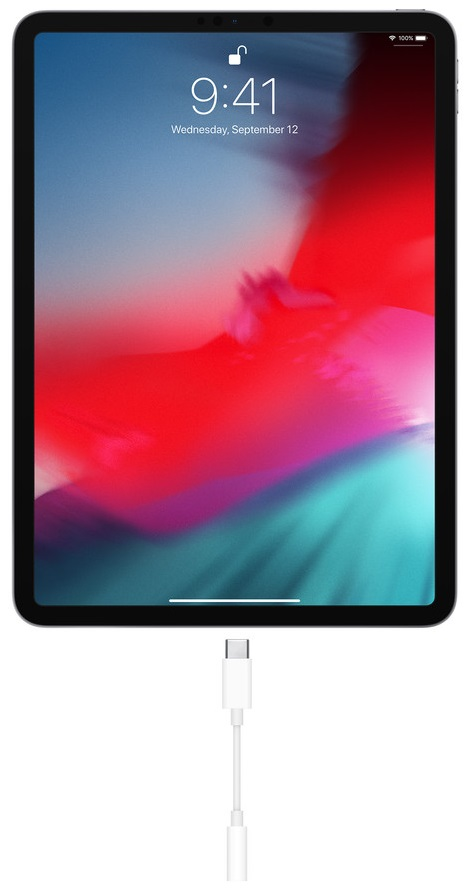 iPad z podłączonym kablem ładującym. Ekran pokazuje kolorową tapetę.