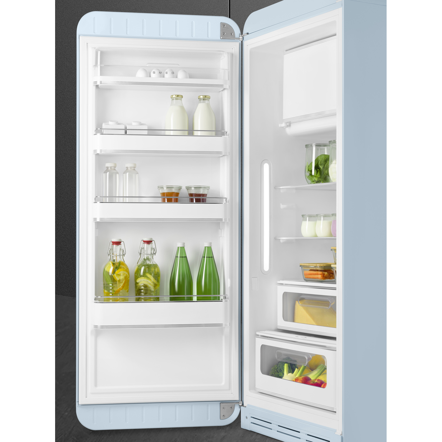Un réfrigérateur SMEG bleu clair avec la porte ouverte, révélant étagères et aliments.