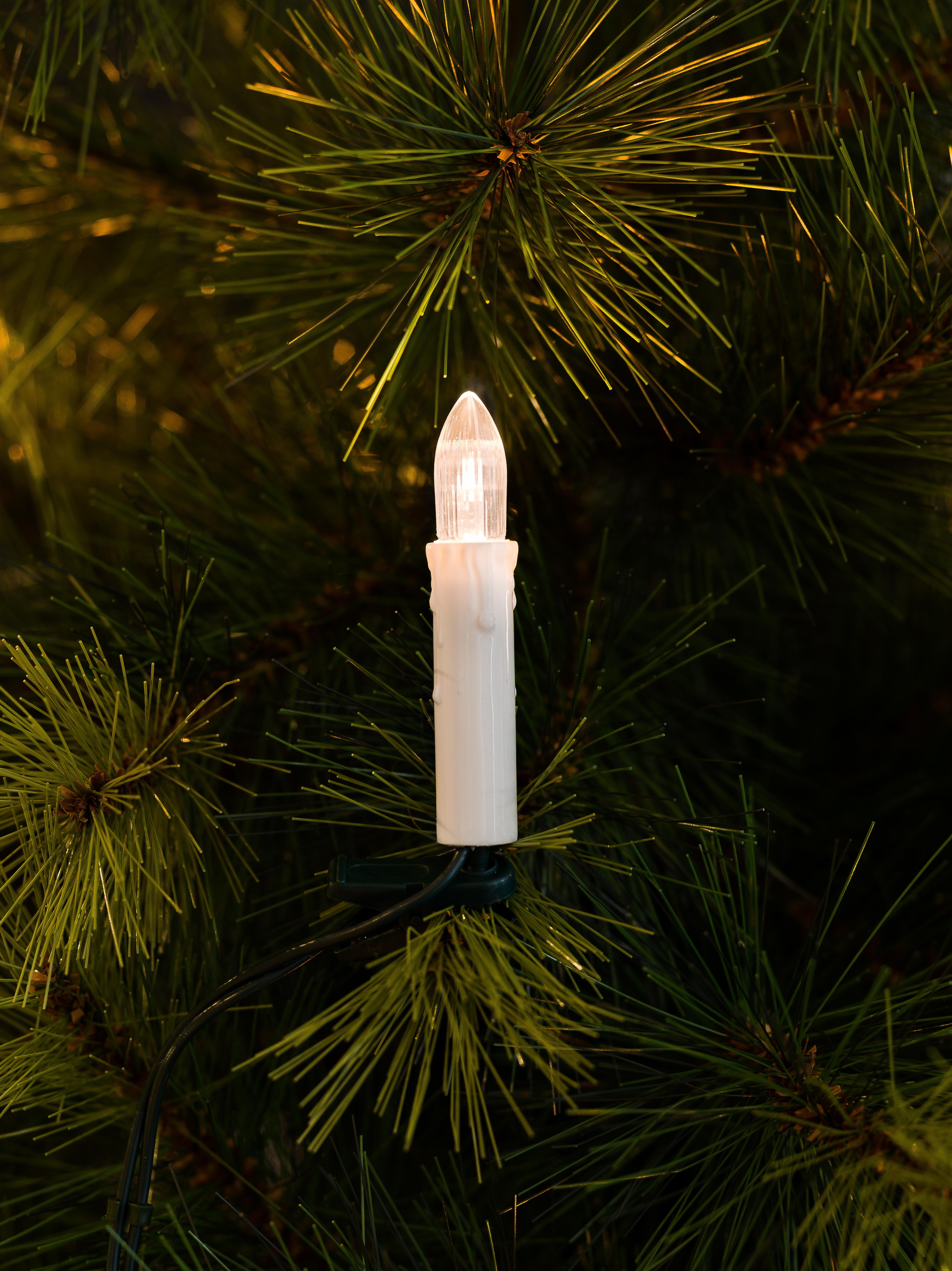 Weihnachtsbaum mit einer beleuchteten weißen Kerzenverzierung.
