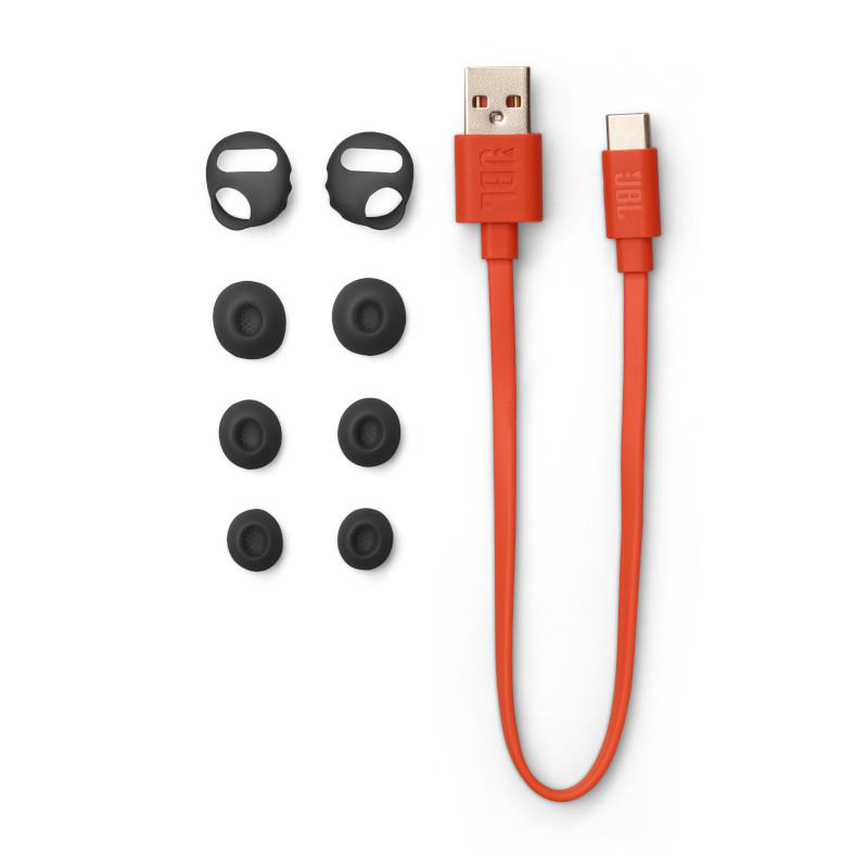 Ohrhörerspitzen, ein Ladekabel und zusätzliche Spitzen liegen vor weißem Hintergrund aus.