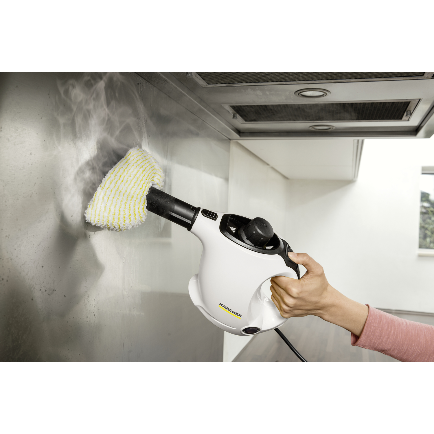 A person cleaning a stainless steel wall with a steam cleaner.