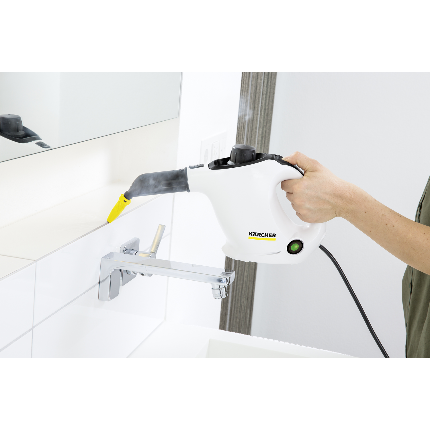 A person using a white Kärcher steam cleaner. The cleaner is near a white tiled wall.