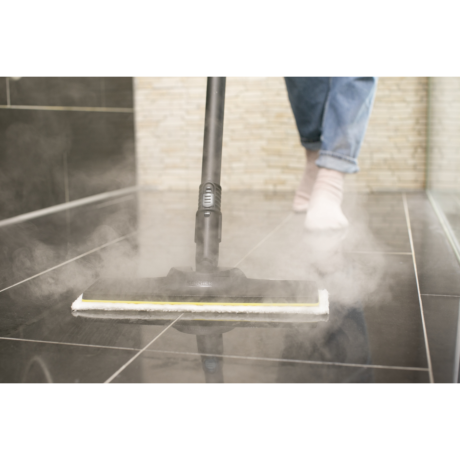 A person cleaning a tiled floor with a steam mop, creating steam.