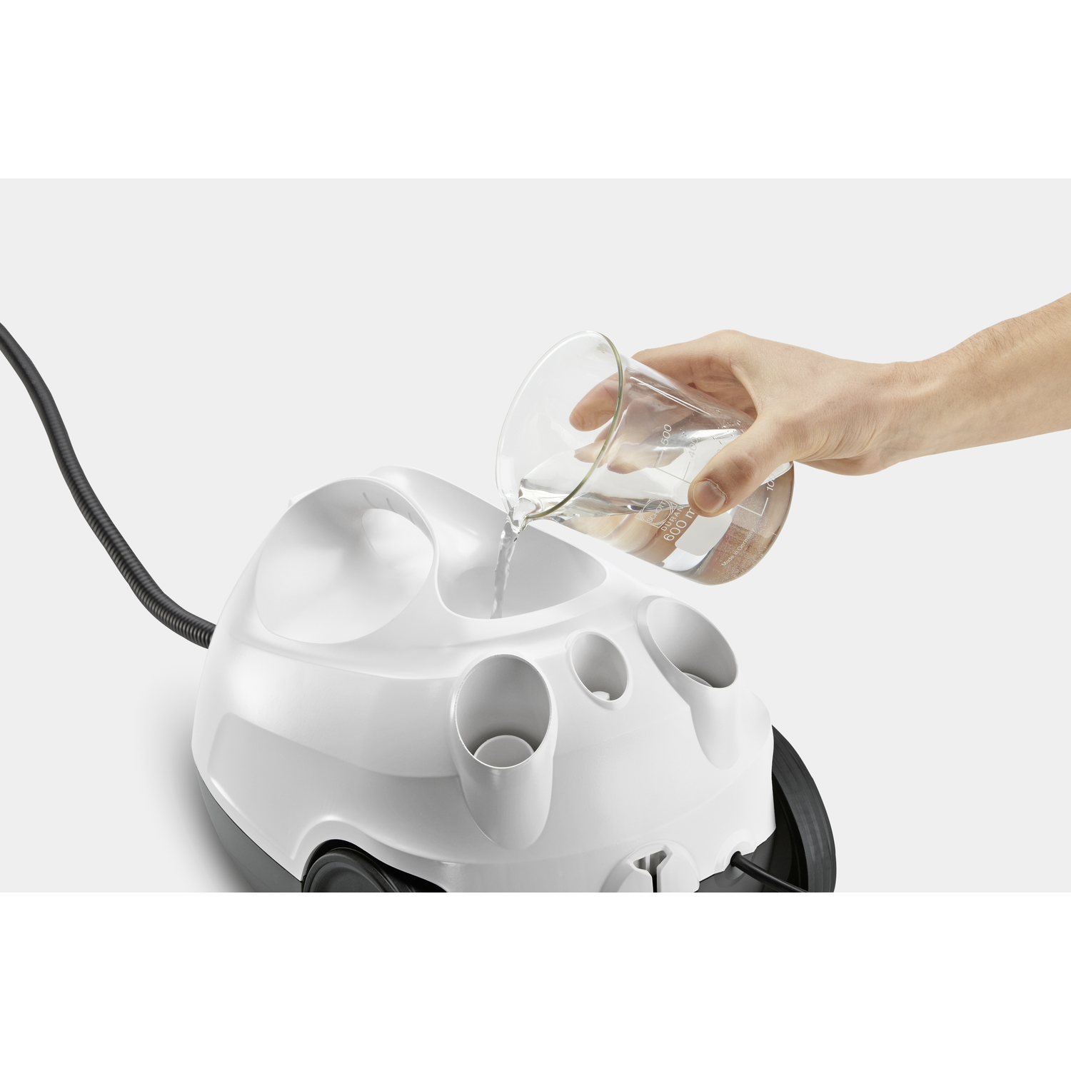 Hand pouring water into a white steam cleaner, close up.