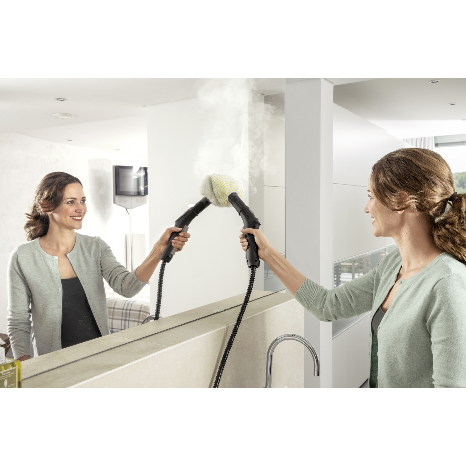 Woman cleaning mirror with a steam cleaner. Reflection shows the woman and interior of the bathroom.