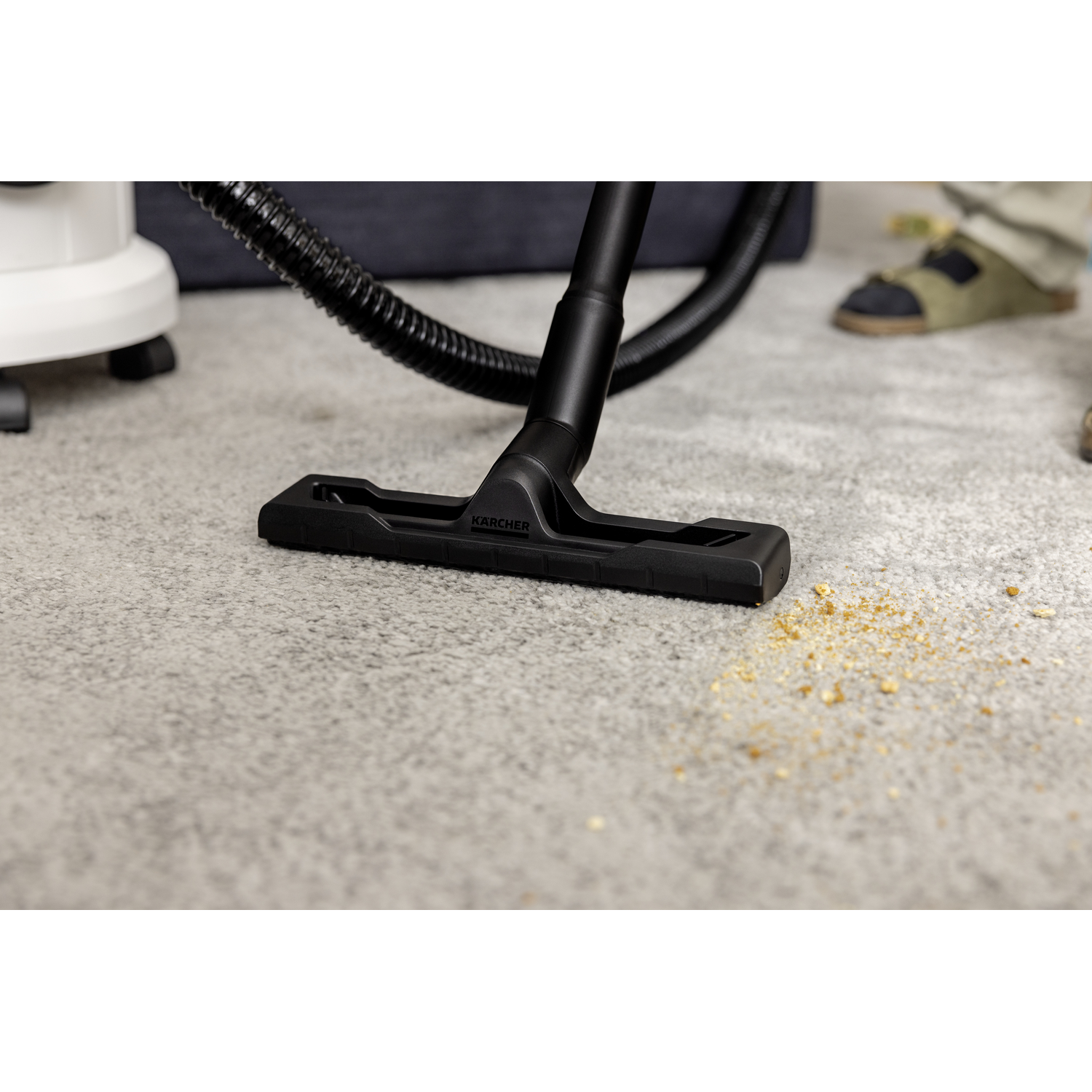 Vacuum cleaner head on carpet. Beige carpet with debris. Black vacuum head.