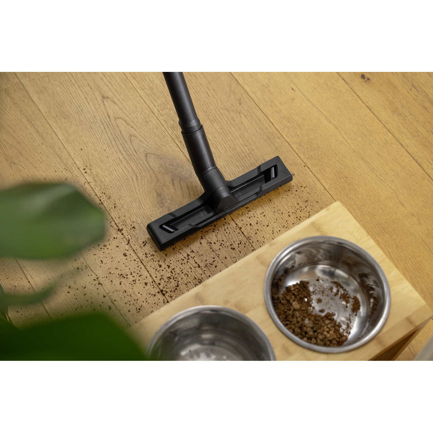 Vacuum cleaner head cleaning a wooden floor. Also shows a wooden bowl with coffee grounds.