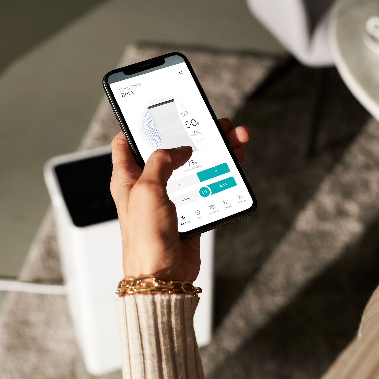Een hand die een smartphone gebruikt met een geopende app, met percentages en instellingen.