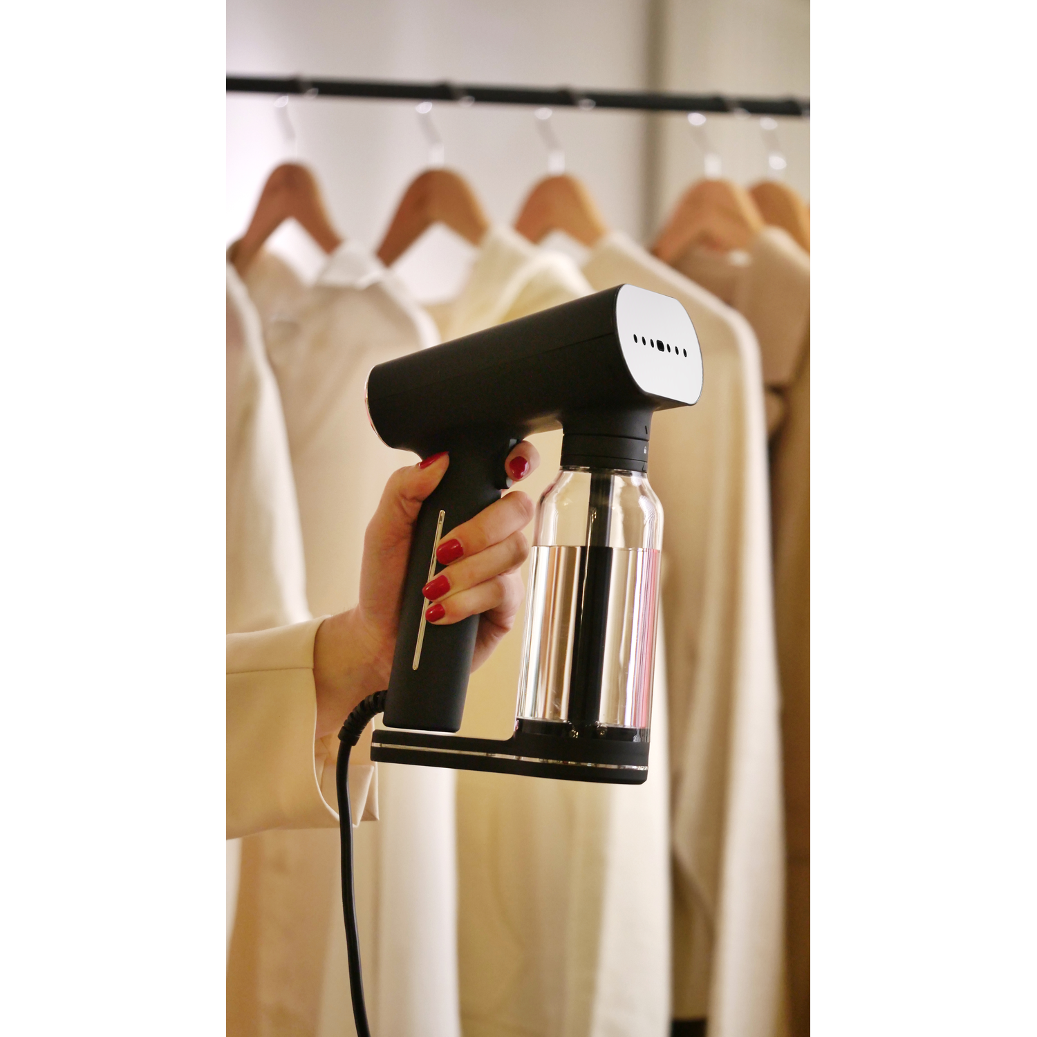 Een hand houdt een zwart-witte kledingstomer vast. Kleding hangt op de achtergrond.