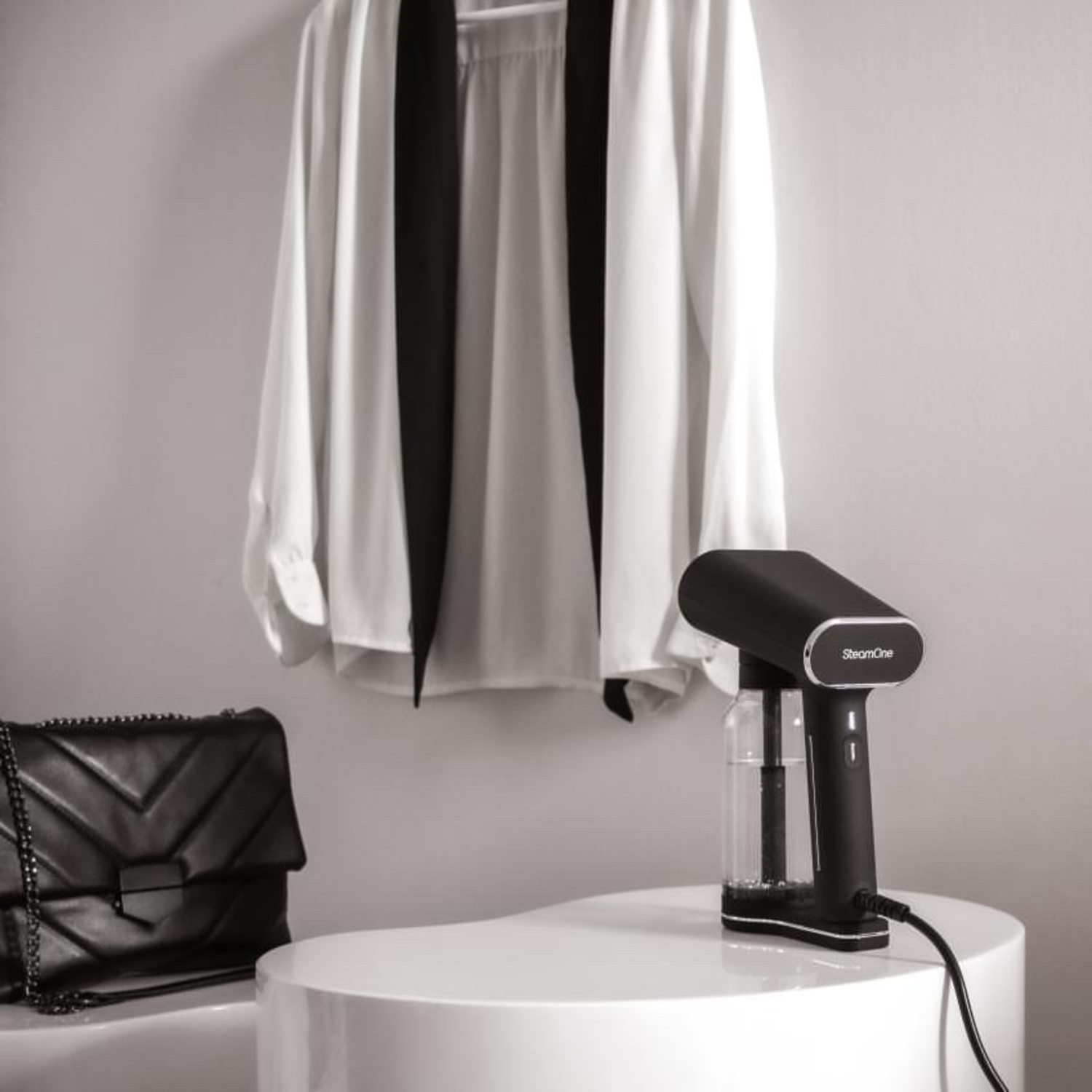 Witte blouse met zwarte sjaal, zwarte tas en zwarte steamer.